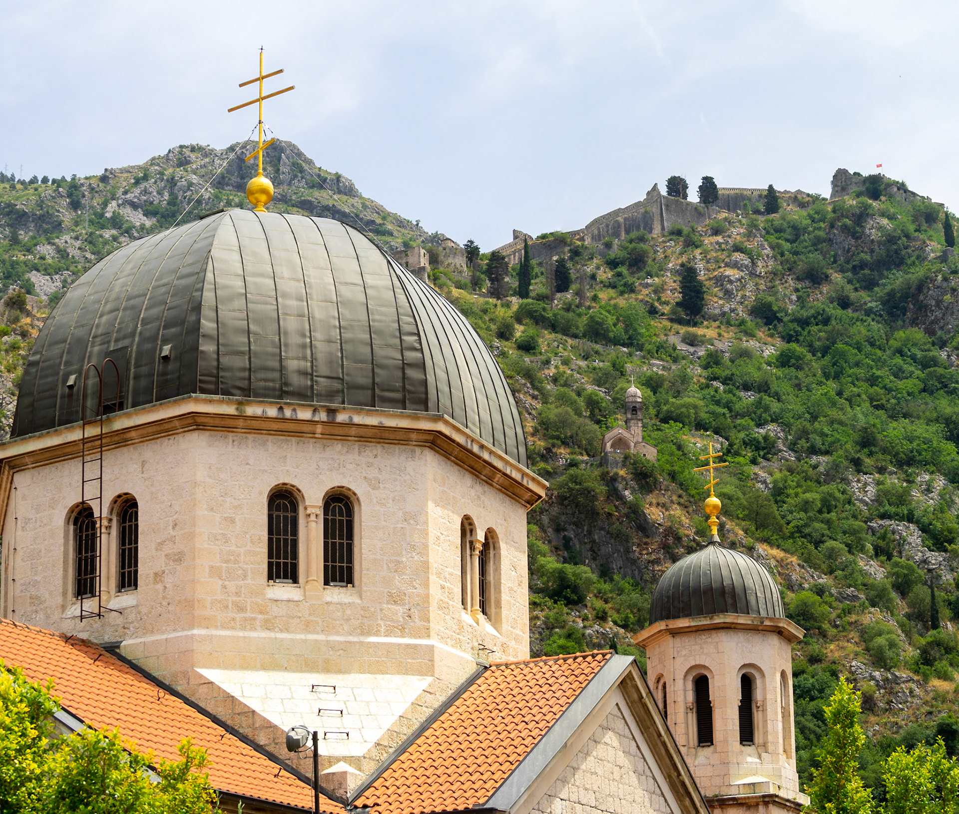 Saint Nicholas’ Church domes with Kotor city wall in the mountain in background