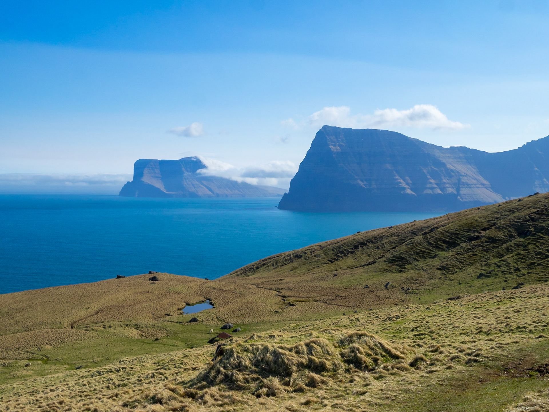 Kallur lighthouse hiking path between the yellow grass landscape of Kalsoy with Kunoy and Vidoy islands at sight