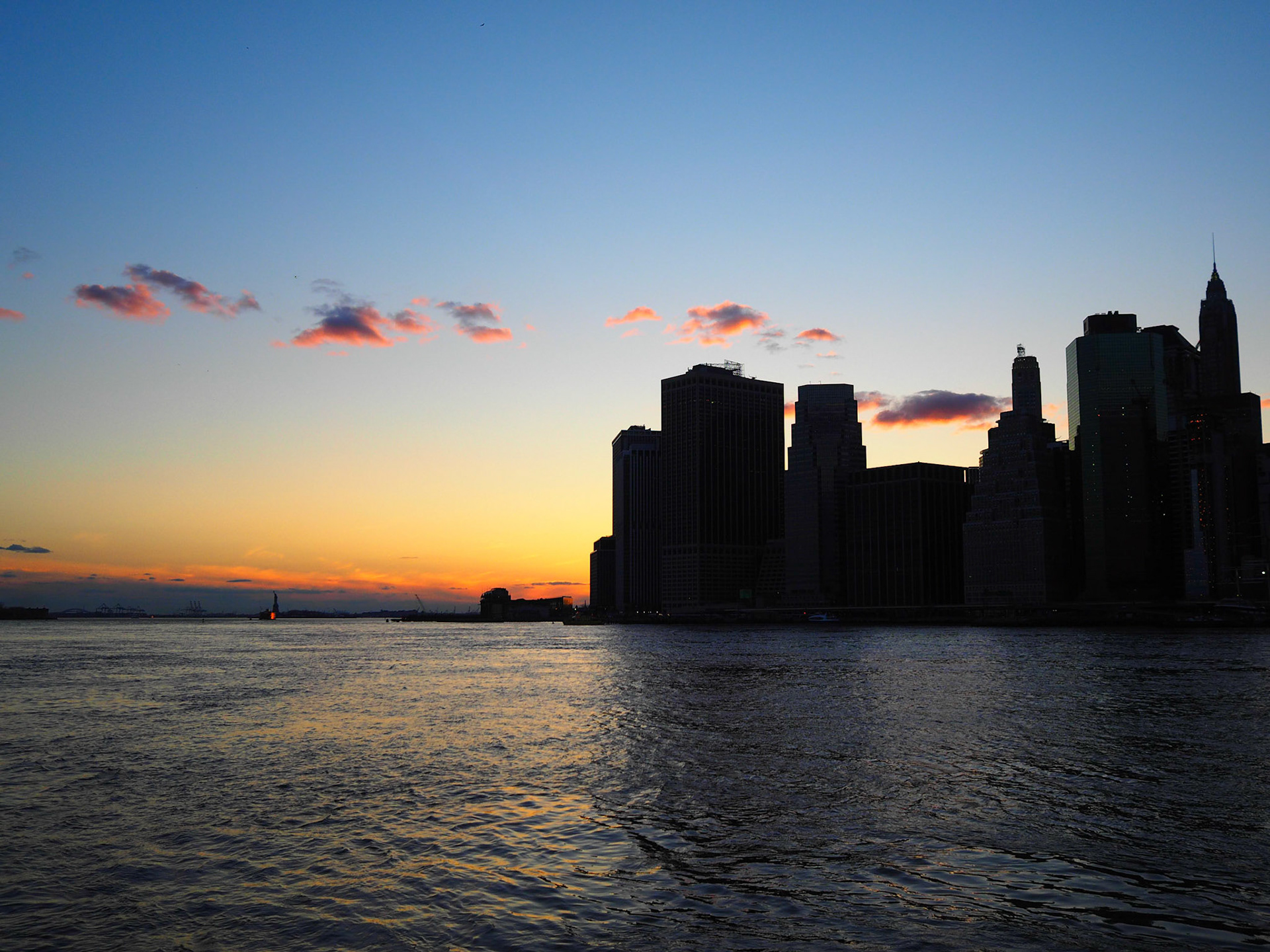 Manhattan skyline silhouette seen from Brooklyn against the sunset sky