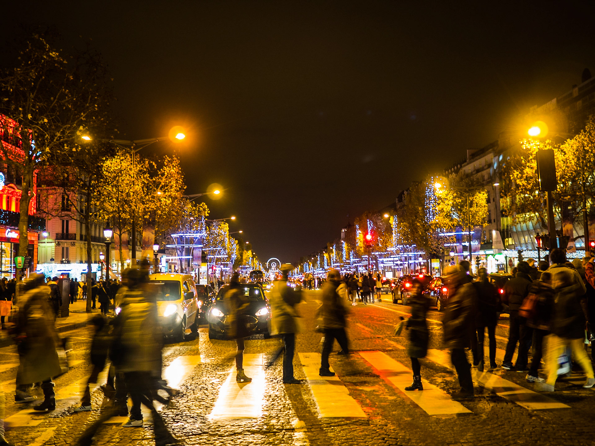 Pedestrians crossing Champs Elysees at night