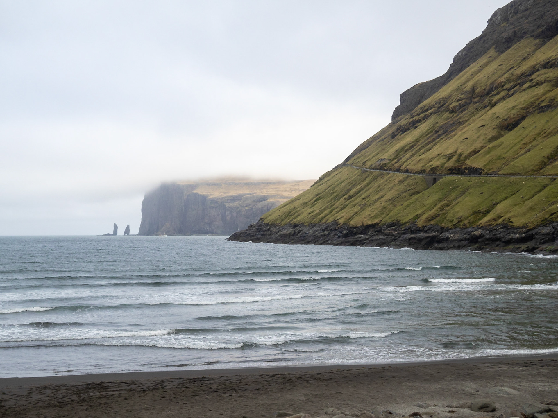 Tjørnuvík black sand beach with Eiðiskollur cliff, and Risin and Kellingin sea stacks, in the horizon
