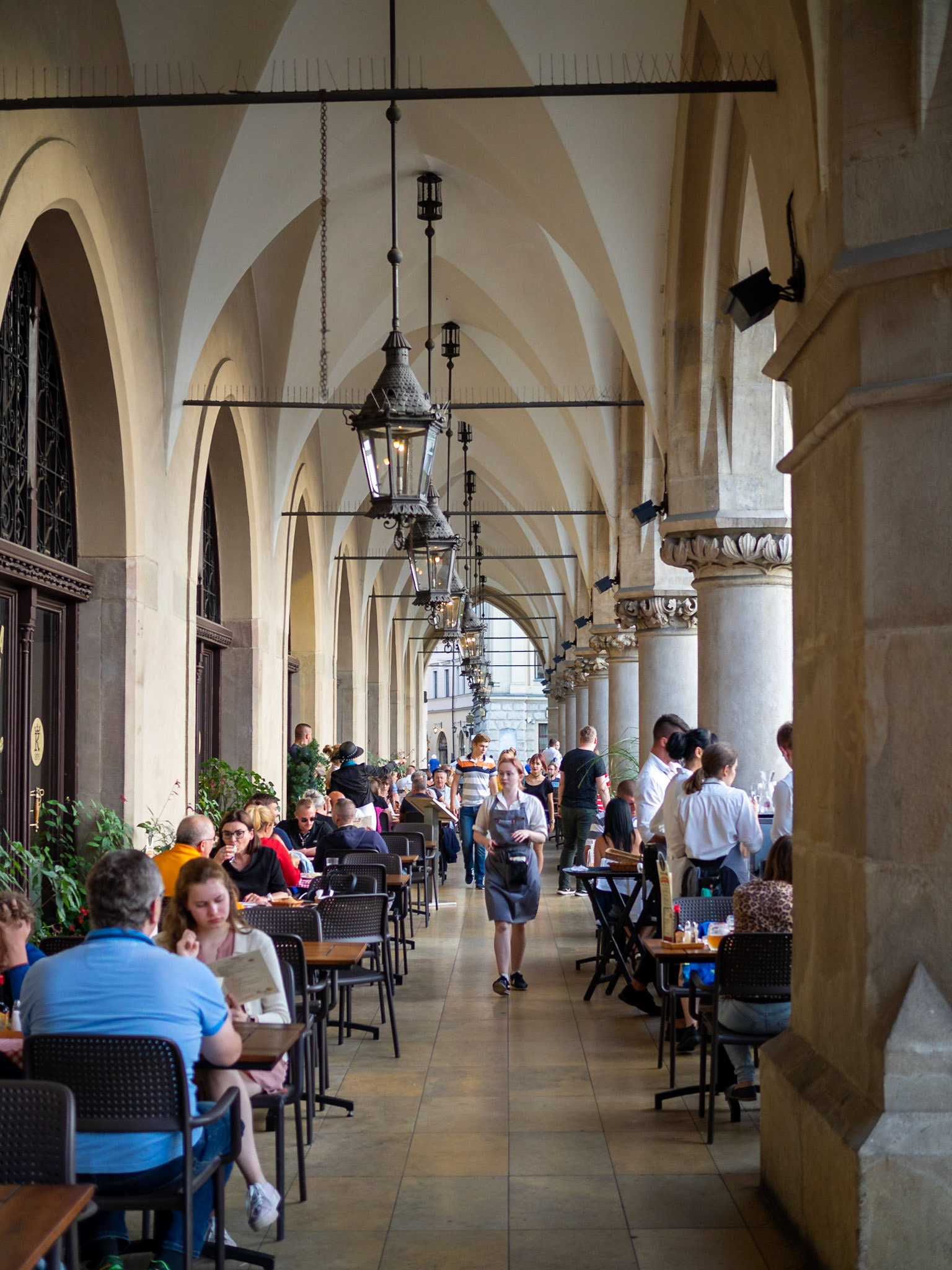 People in the cafes under the archway of Krakow's Cloth Hall