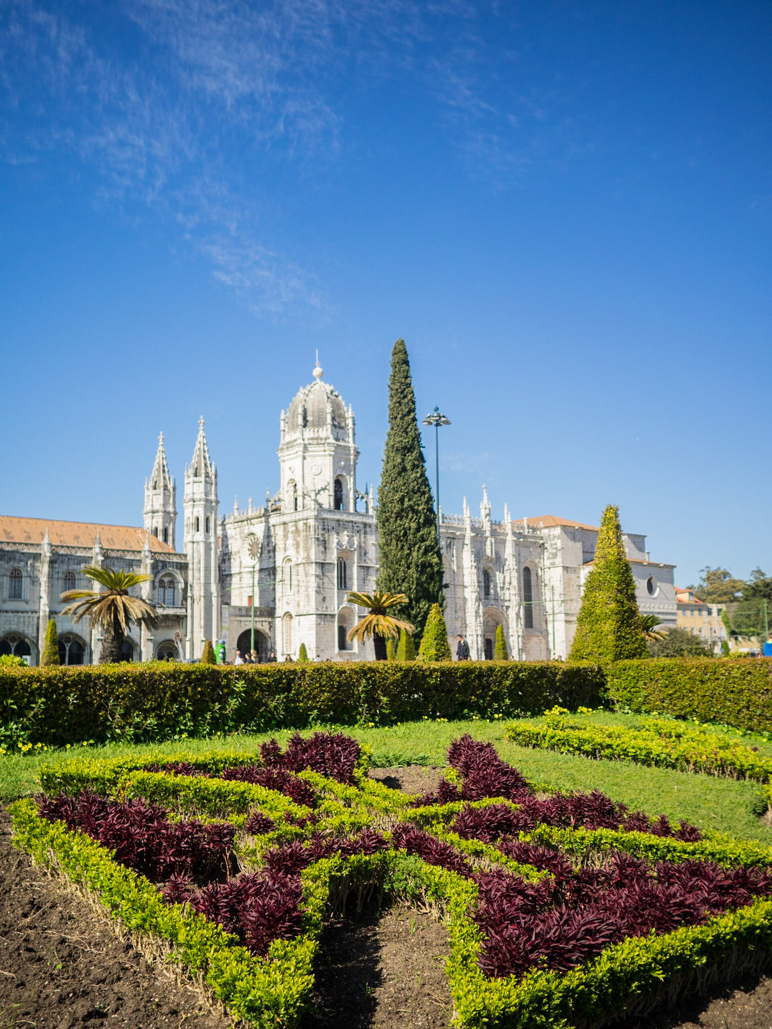 Cross cut in the bushes with Jeronimos Monastery in background