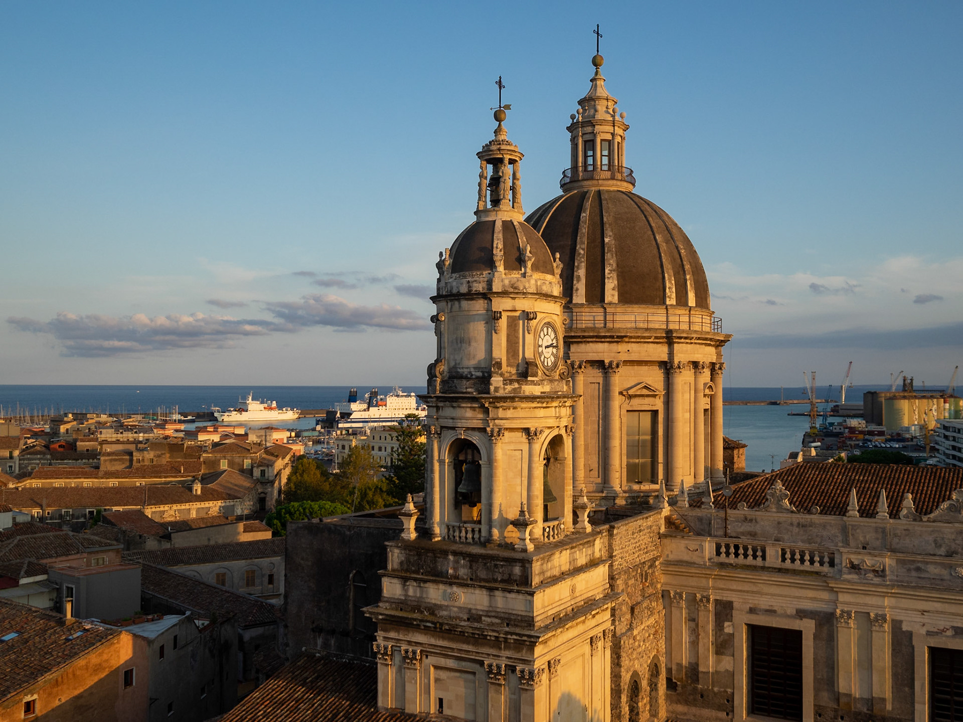Catania Cathedral dome and tower over the city roofs with the port in background