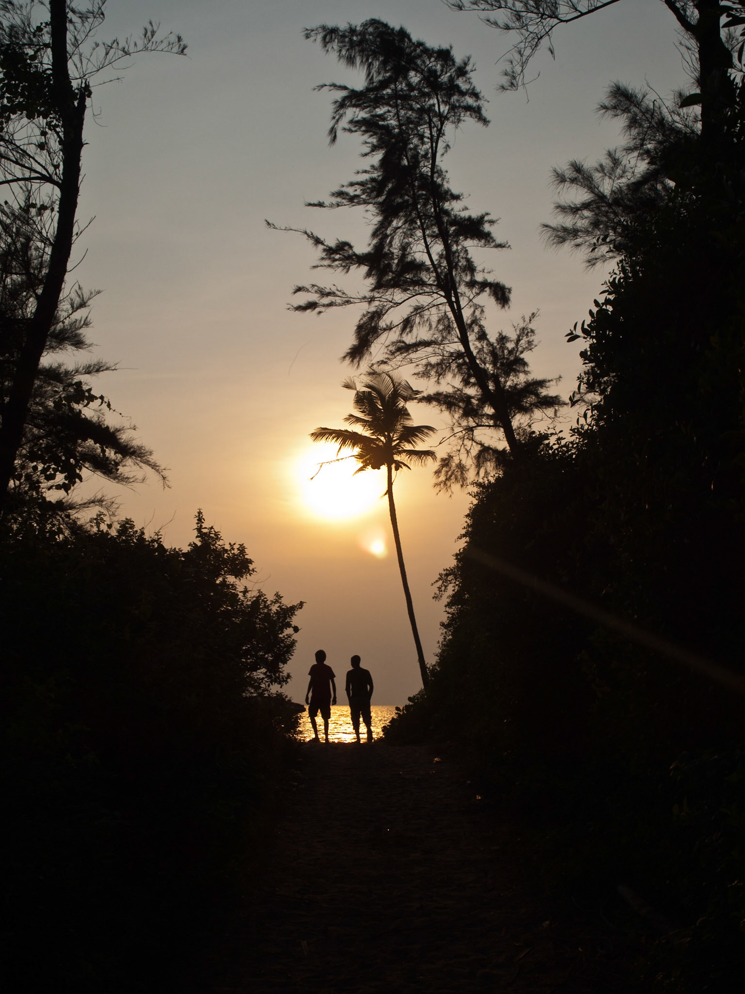 Two man walk towards the sunset in a goan beach