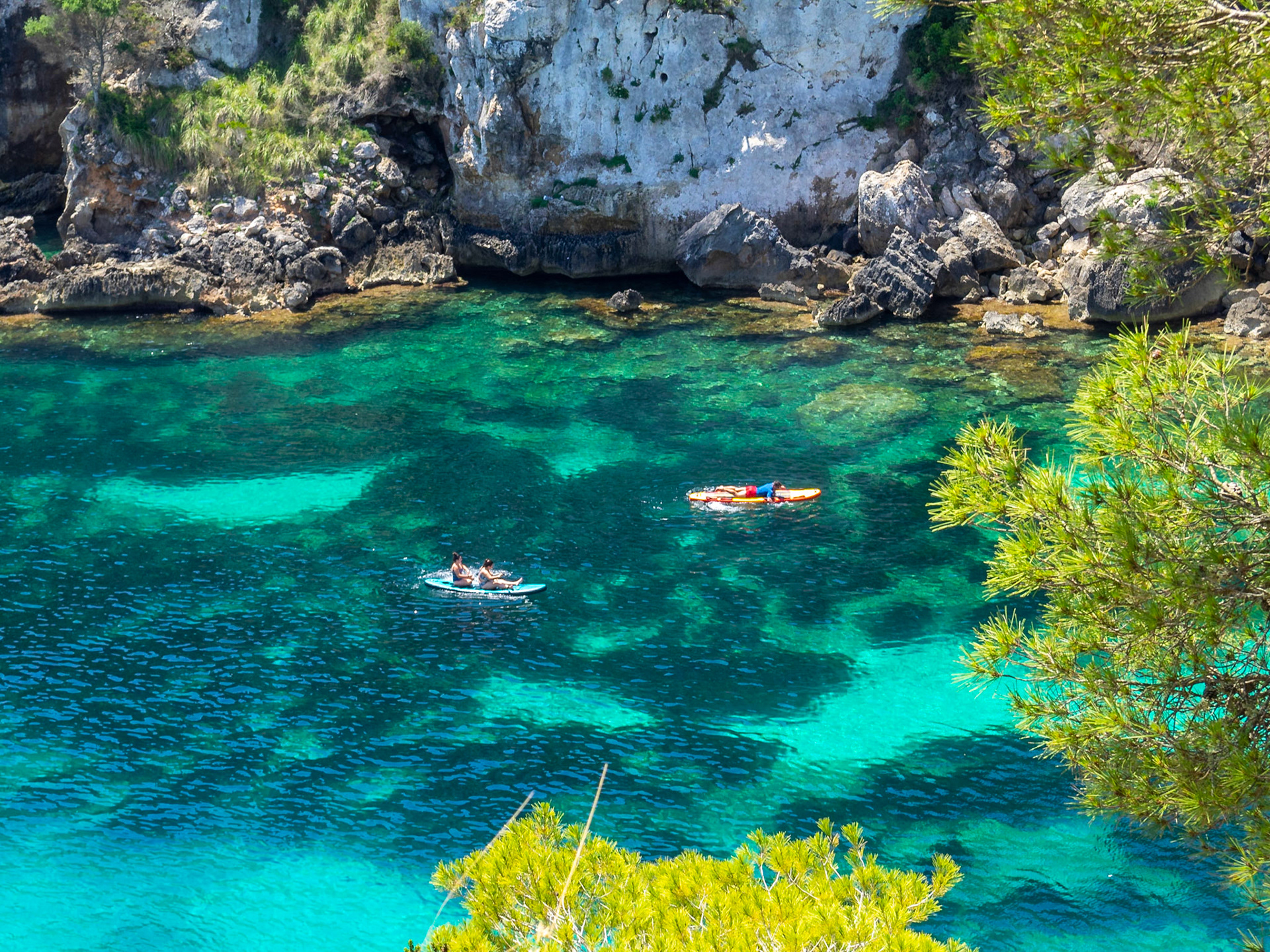 Beach goars floating over the turquoise waters of Cala Macarelleta