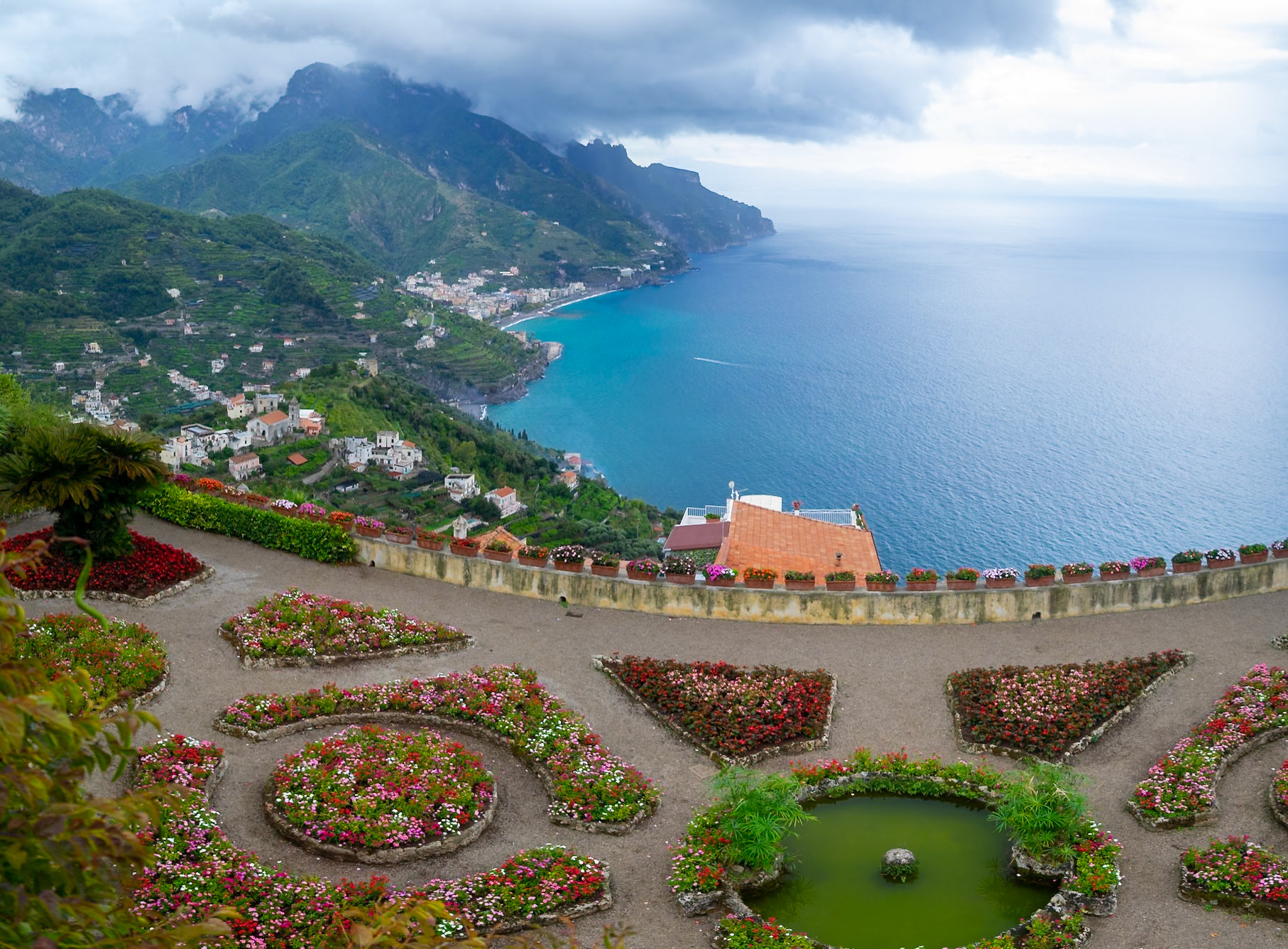 Colorful flower beds of Villa Rufolo belvedere garden with Amalfi Coast in background, Ravello
