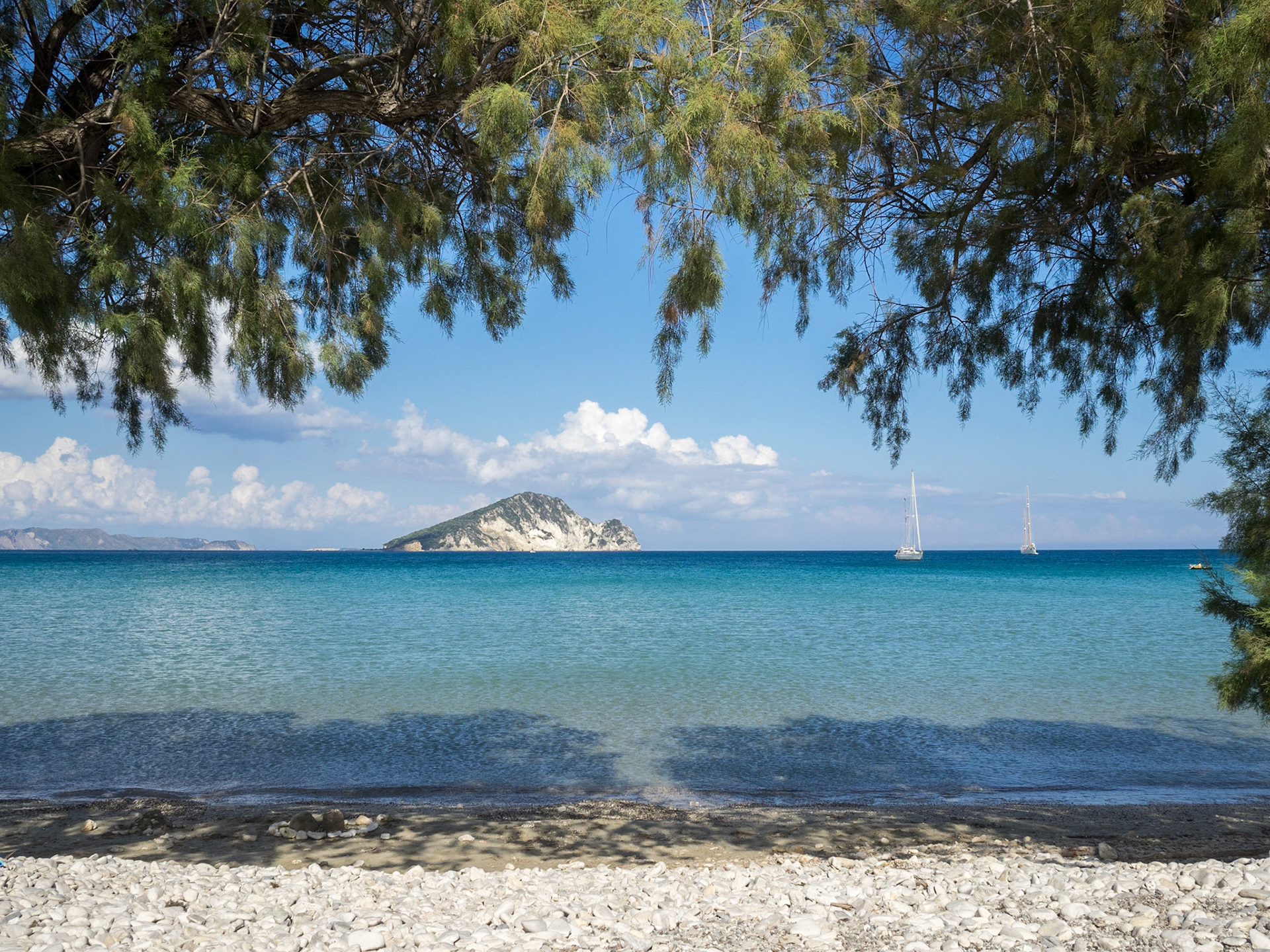 White pebbled and turqoise waters of Keri beach framed by trees