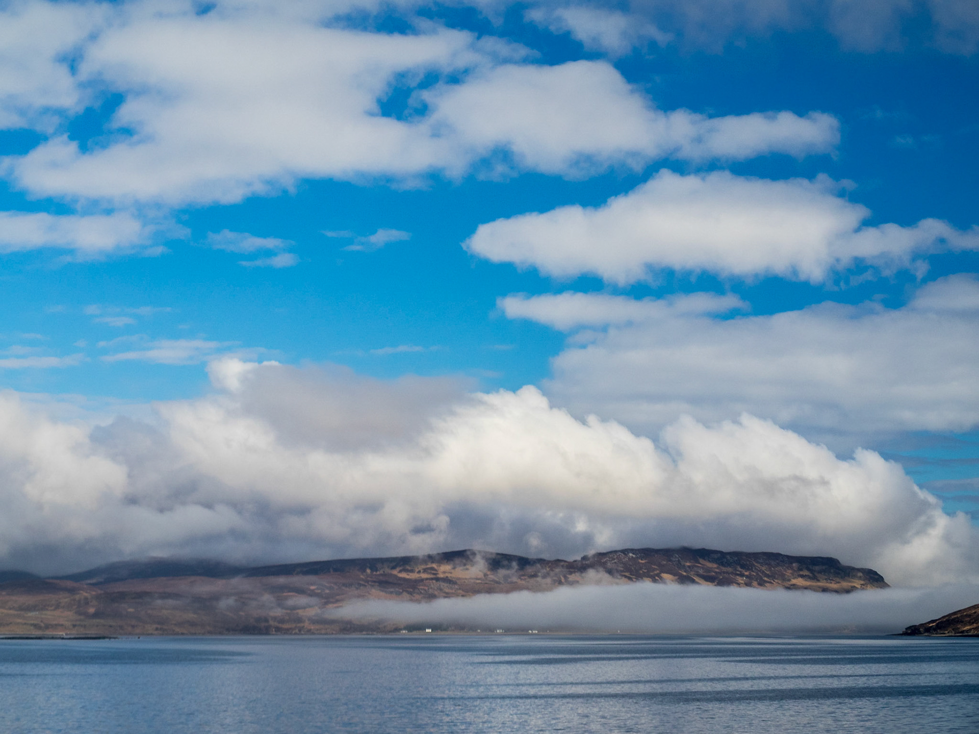 Low clouds over the sea below the blue sky