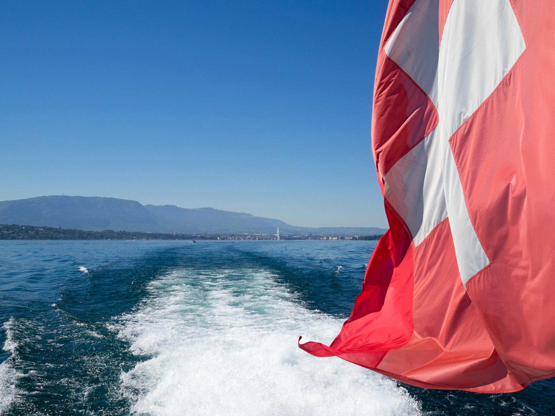 Swiss flag waving over Lake Geneva