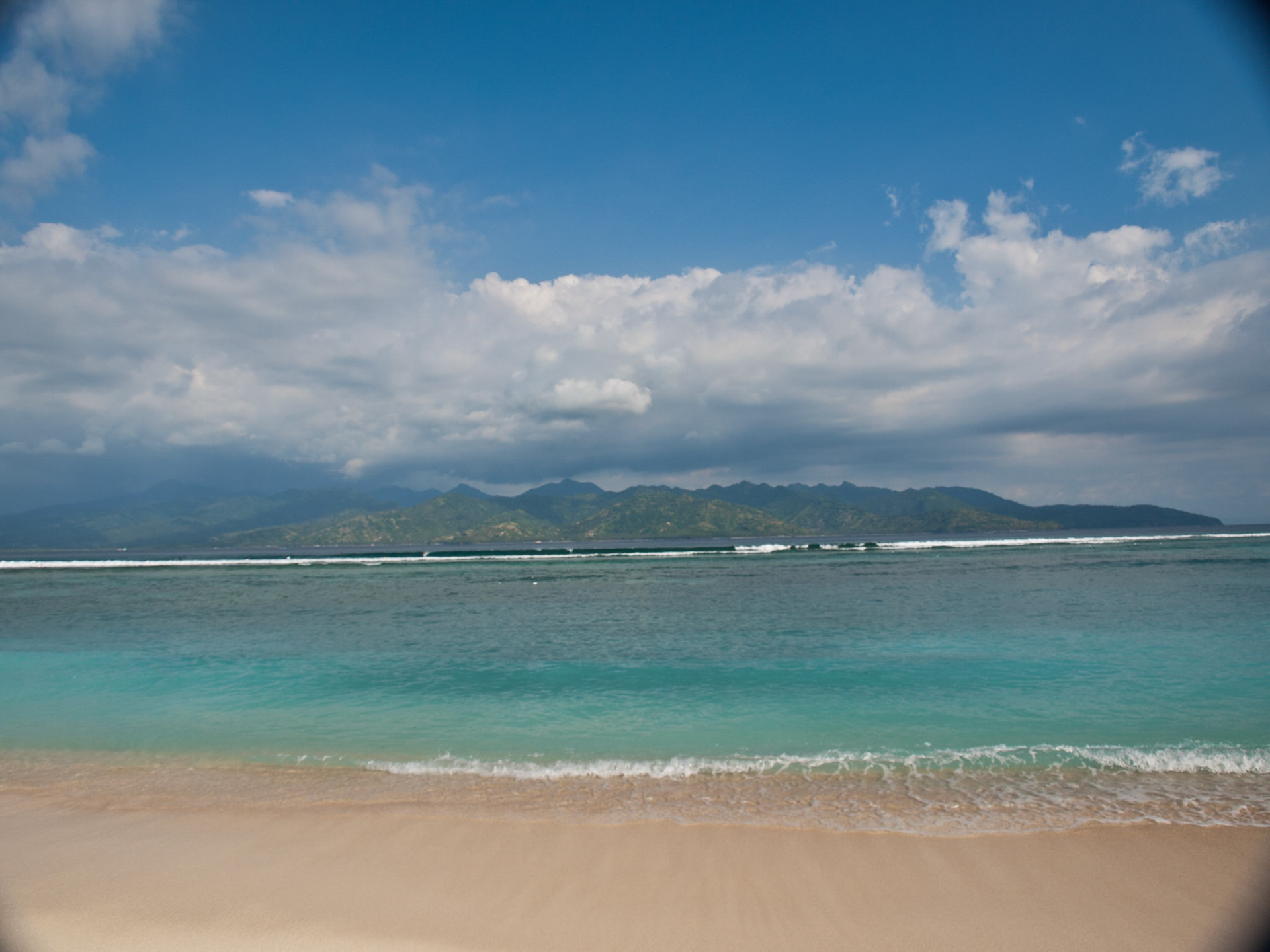 Gili Trawangan tropical sea beach with Lombok island in background with white clouds above