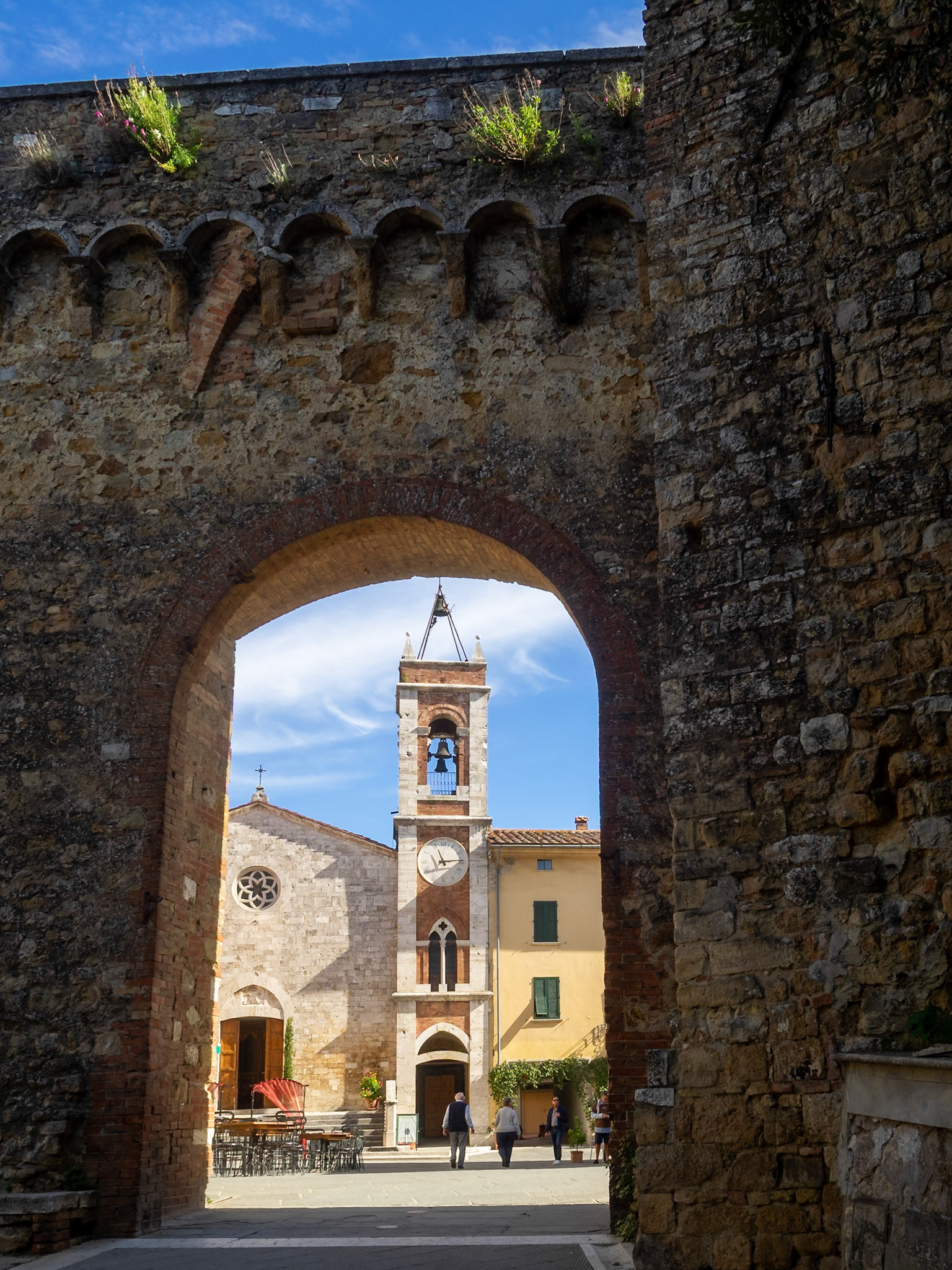 St. Francis Church framed by a gate of the city wall, San Quirico d'Orcia