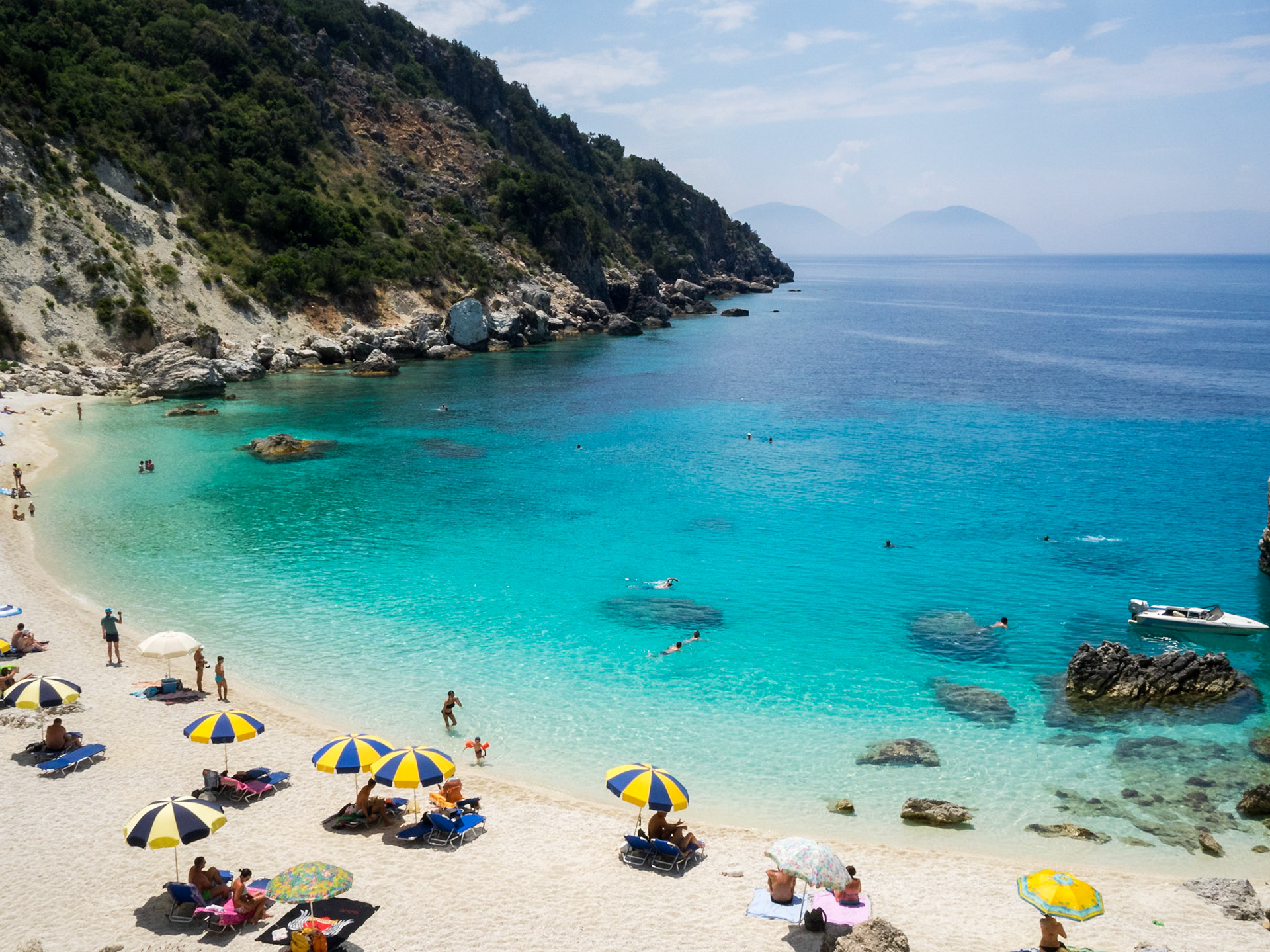 View of Agyofili  turquoise sea with sun umbrellas by the edge