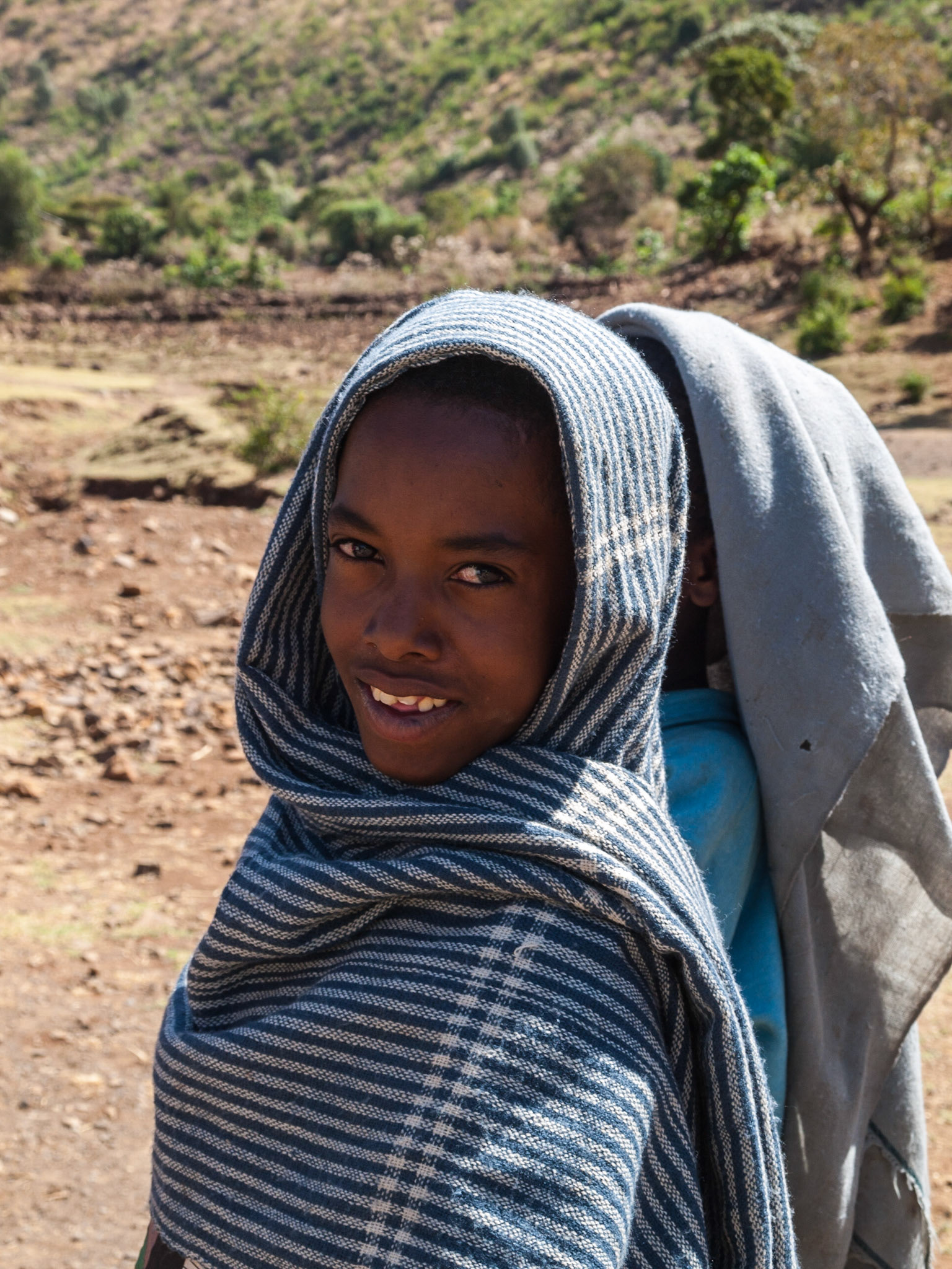 Ethiopian boy with covered head smiles at camera