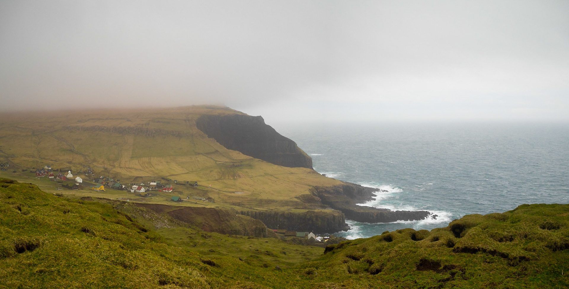 Mykines village by the sea between the grass fields seen from Mykineshólmur