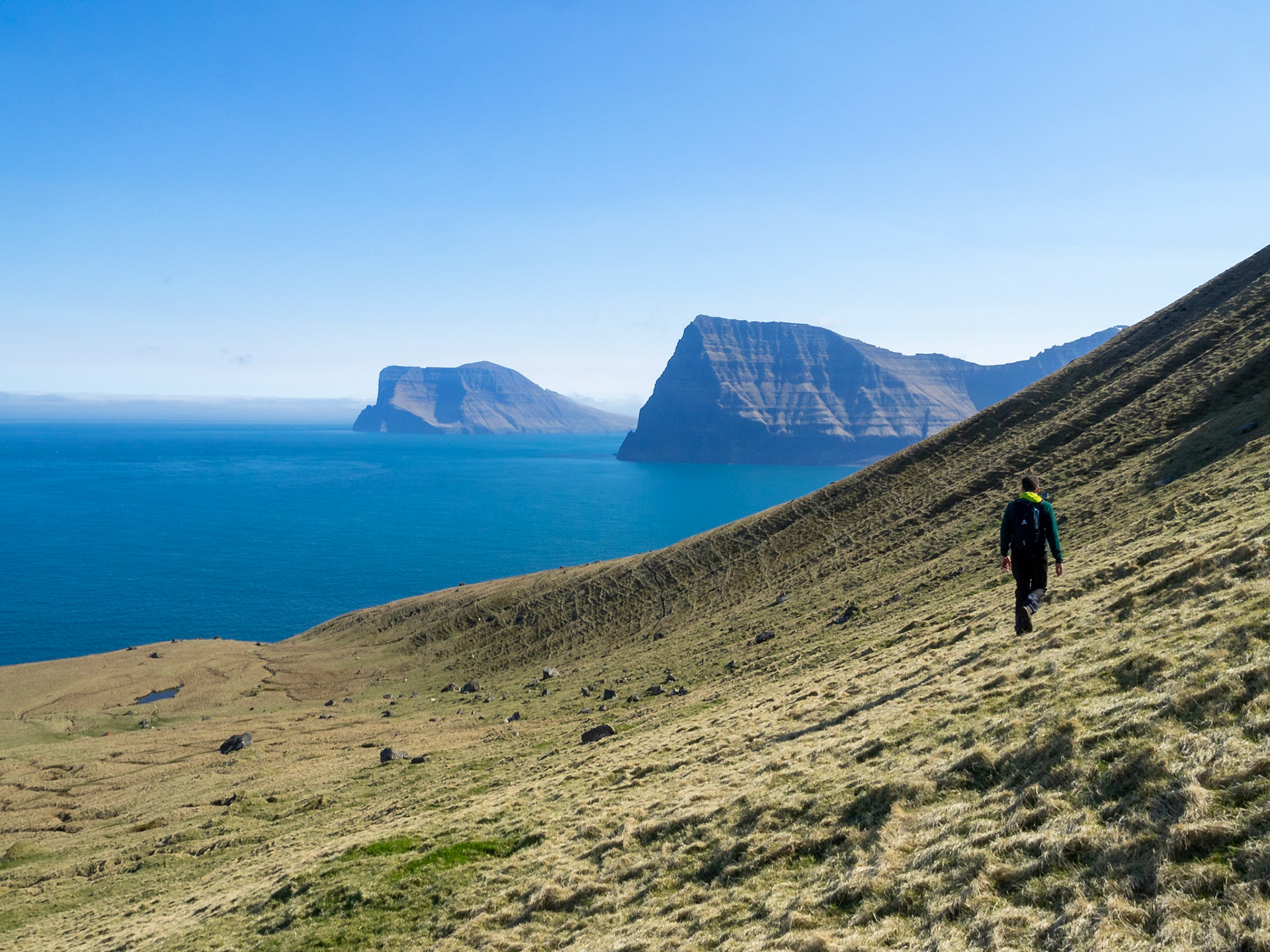 Hikking the mountain slop in north Kalsoy with Kunoy and Vidoy islands in the horizon
