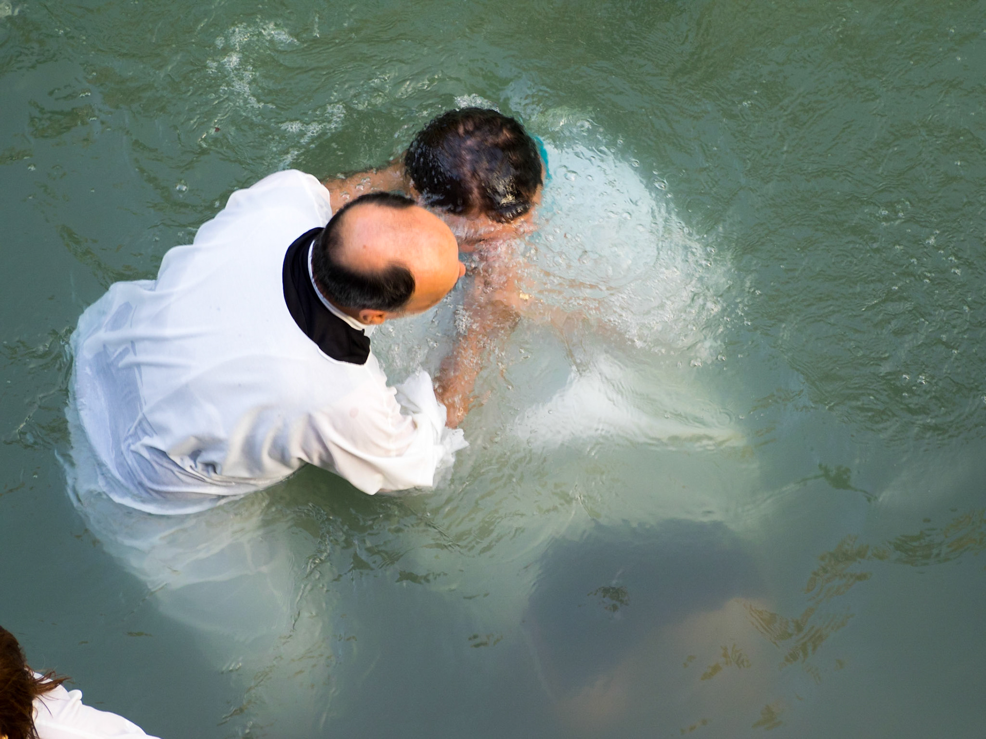 Christian priest baptizing a man in Yardenit baptismal site in Jordan river