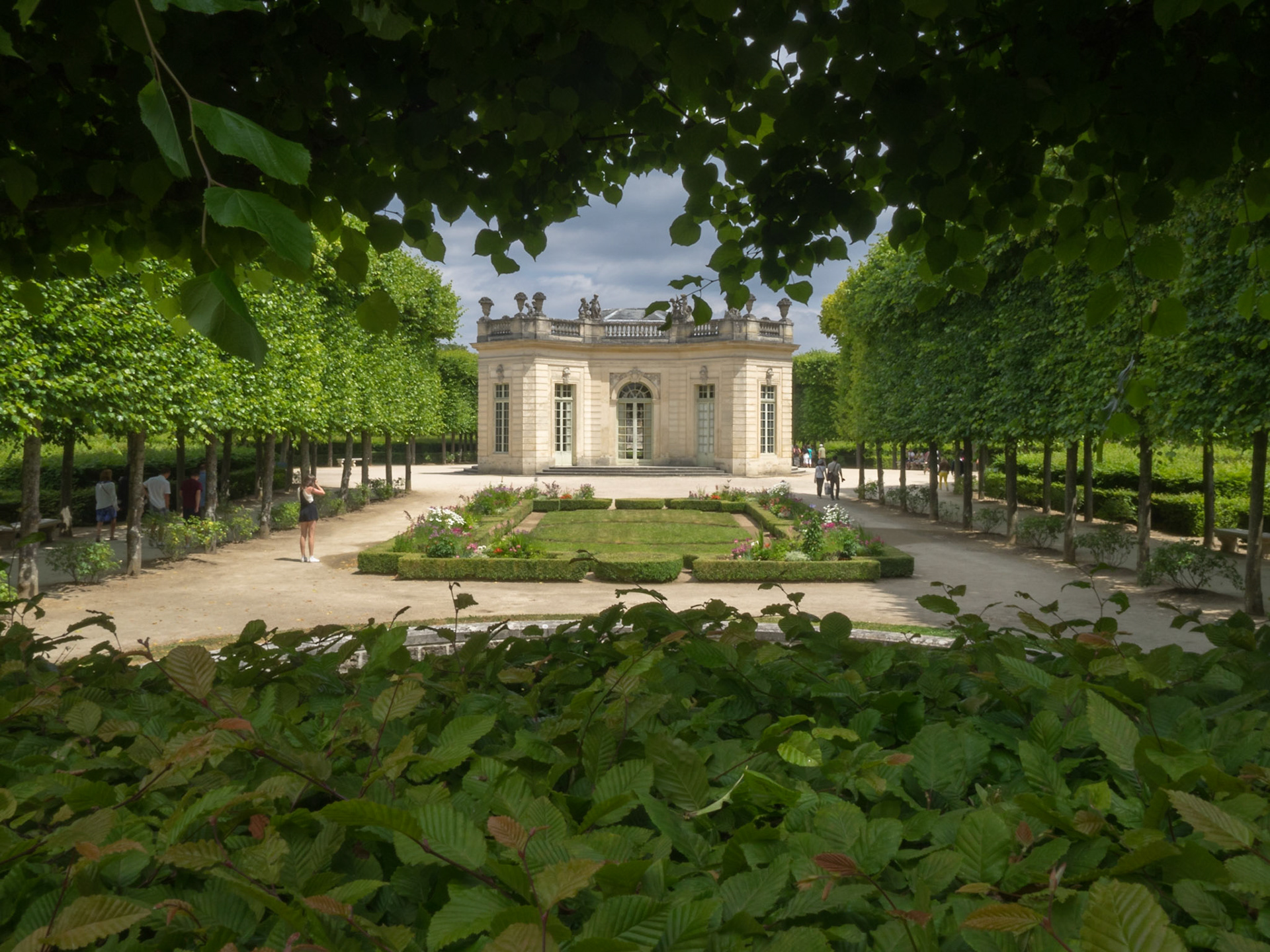 The Petit Trianon French Pavilion building between the garden foliage