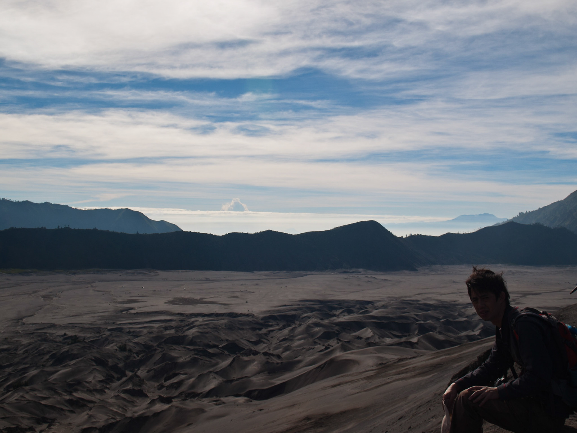 Tourist on the edge of Bromo crater looking at the sea of sand