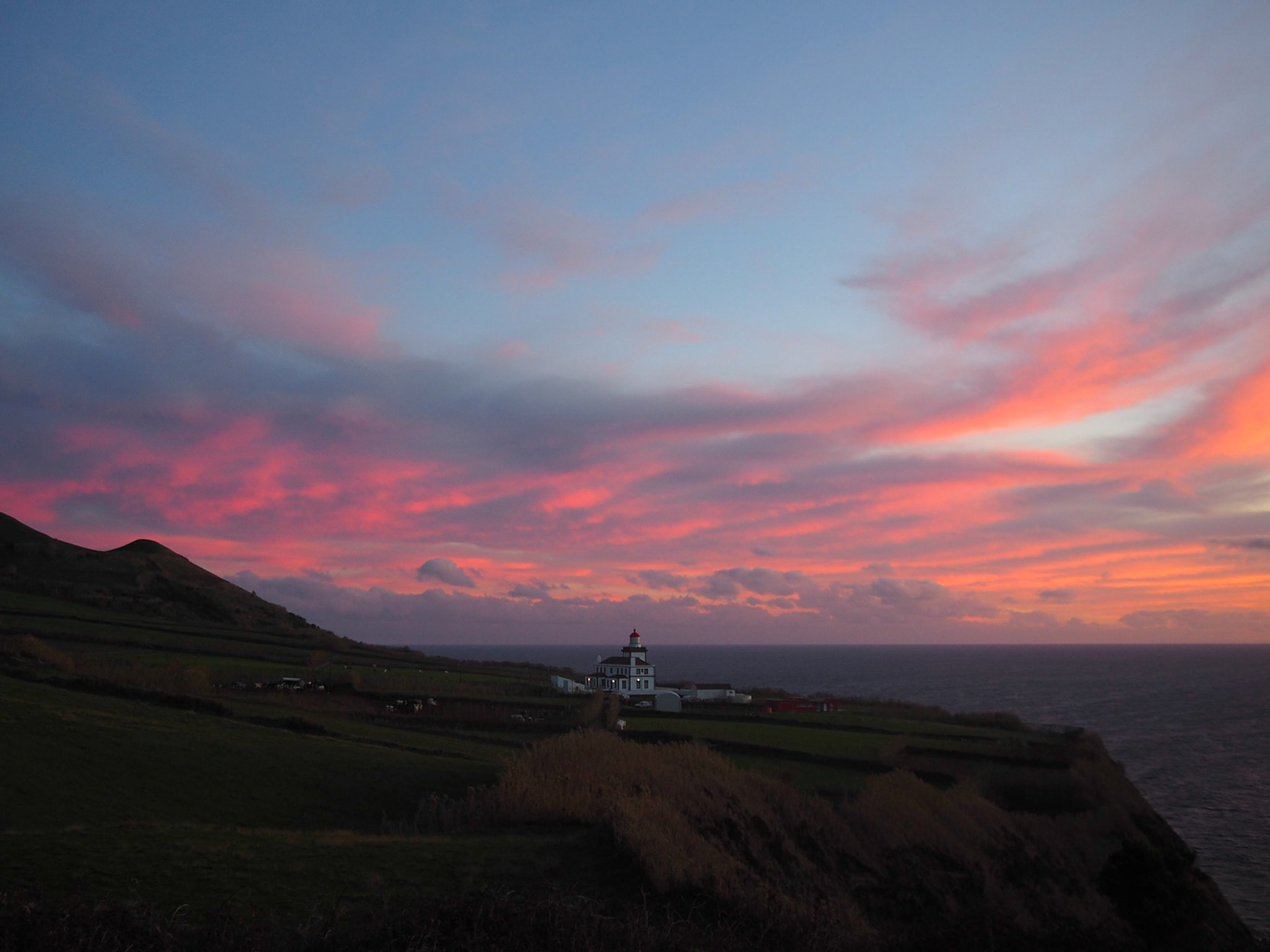Pink sky over the Atlantic Ocean by a lighthouse in Sao Miguel island