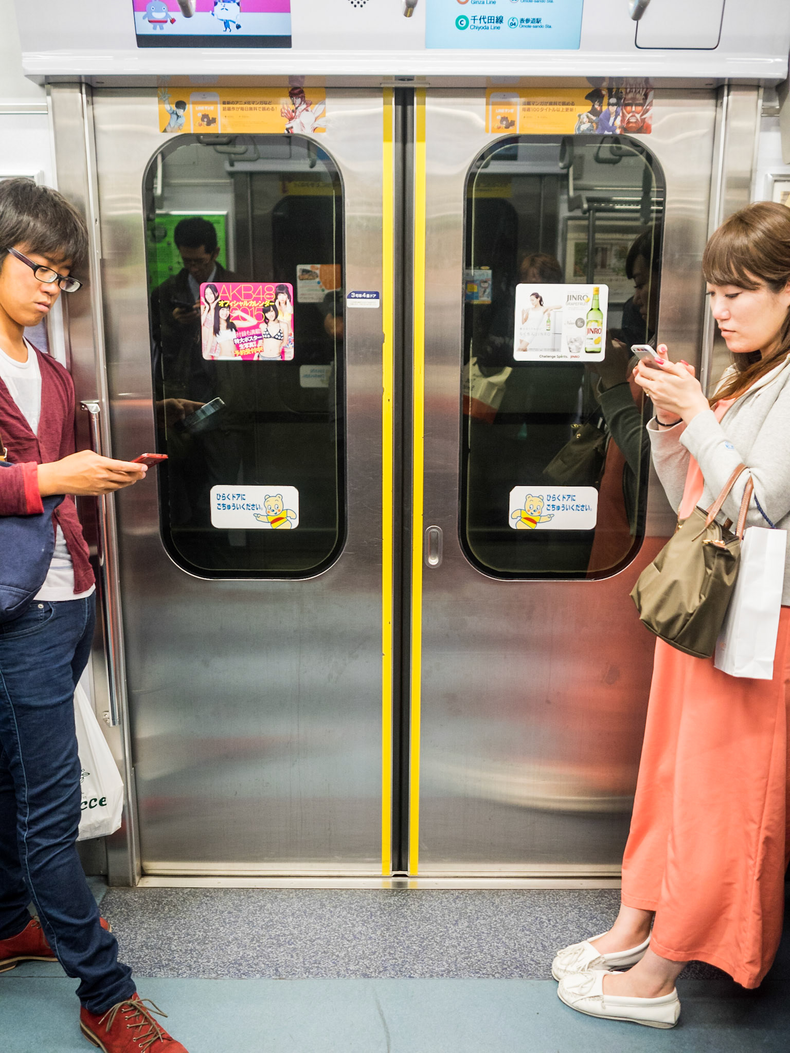 People on Tokyo underground looking at mobile phone