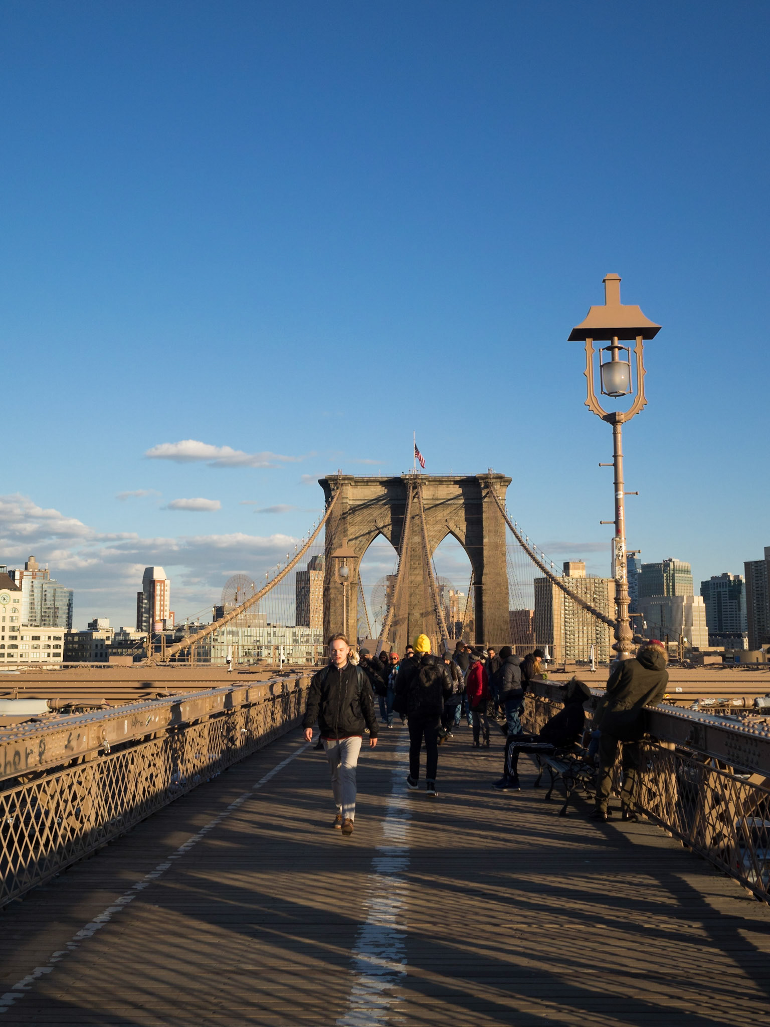 People crossing the Brooklyn Bridge in the sunset light