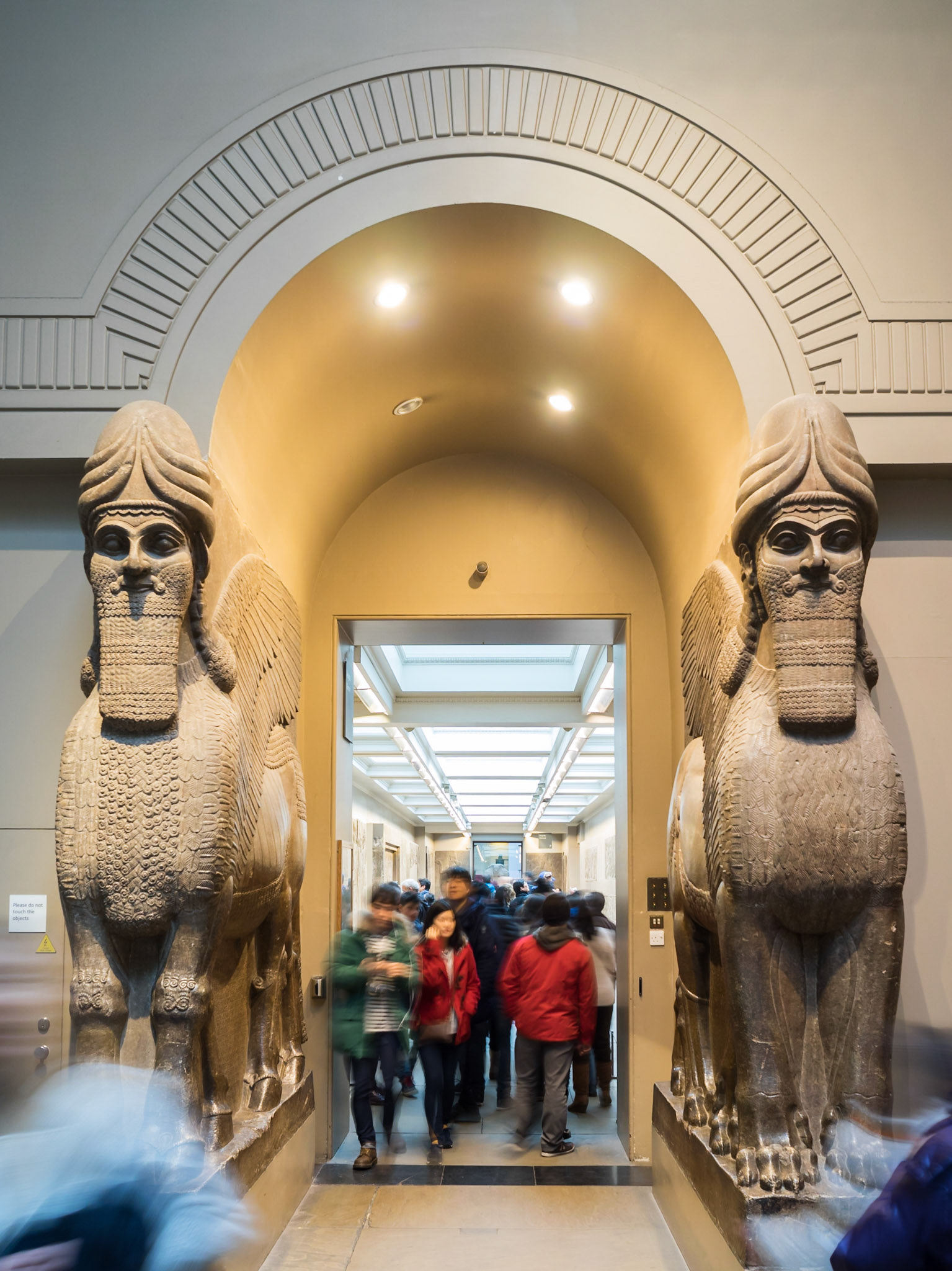 Visitors passing by the Assyrian Gateway Human Headed Winged Lions 'Lamassu' at the British Museum
