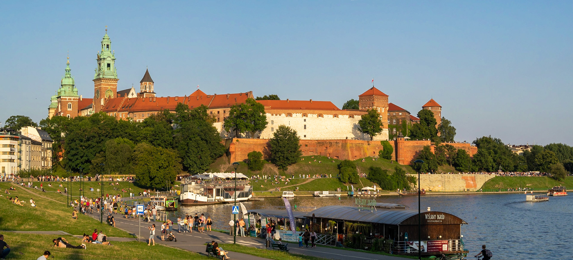 People enjoying the sun by Vistula river and Wawel Castle, Krakow