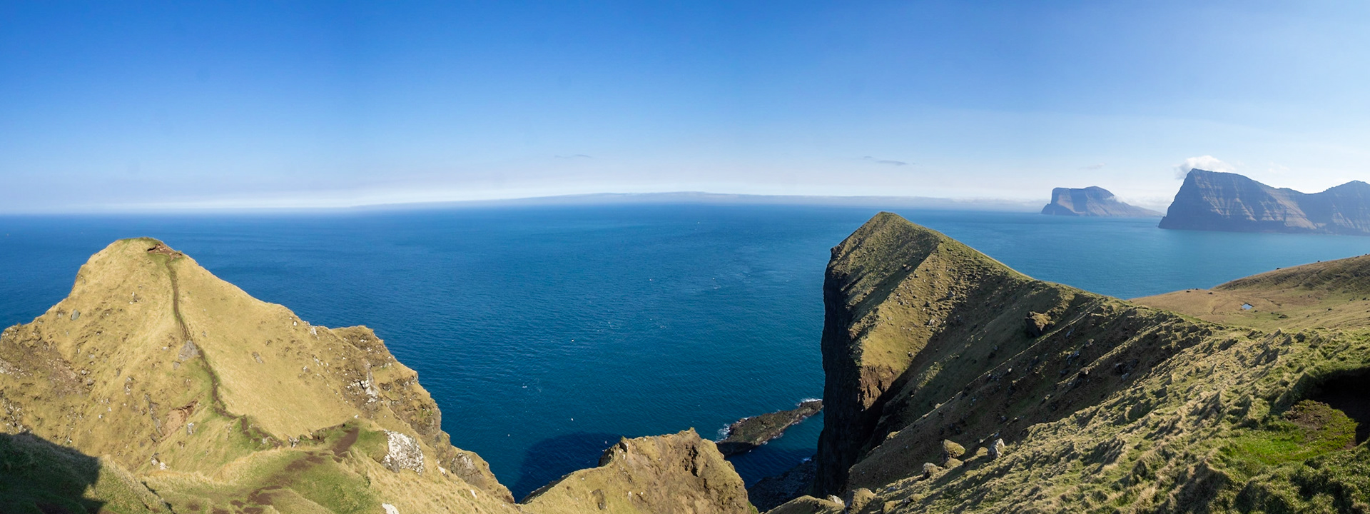 Kallur lighthouse hiking path by the cliffs edge of north Kalsoy, with Kunoy and Vidoy islands at sight