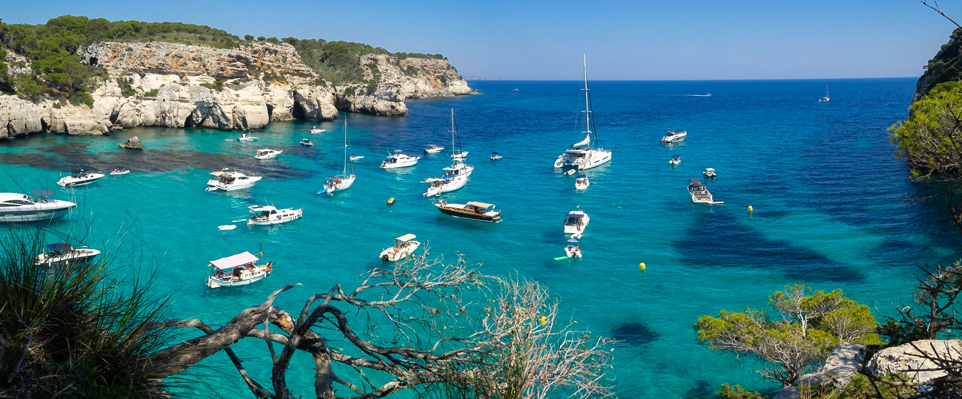 Boats floating over the turquoise waters of Cala Macarelleta, Menorca