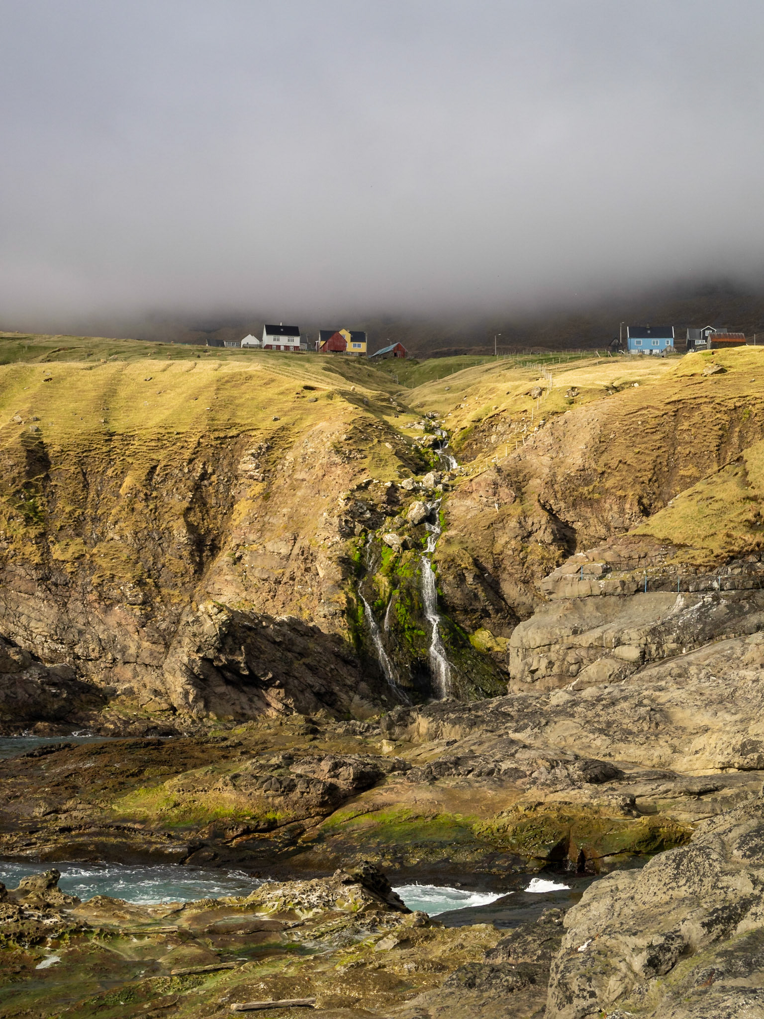 Houses below the low clouds and over the coastline on north Vidoy