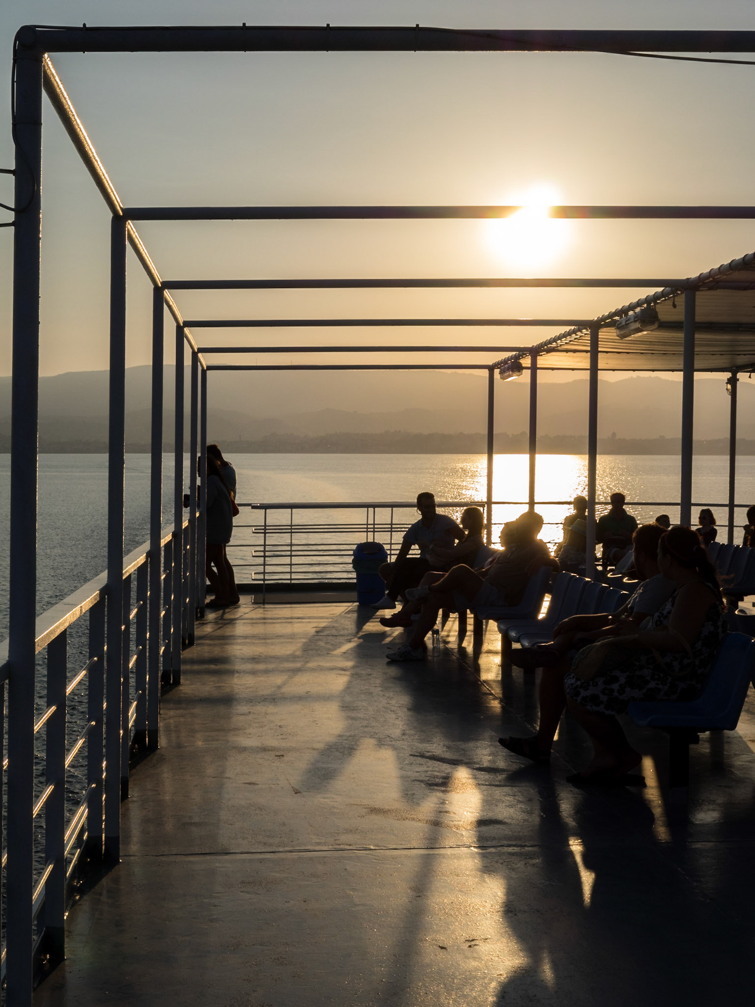 Silhouettes of ferry passengers in the sunset light