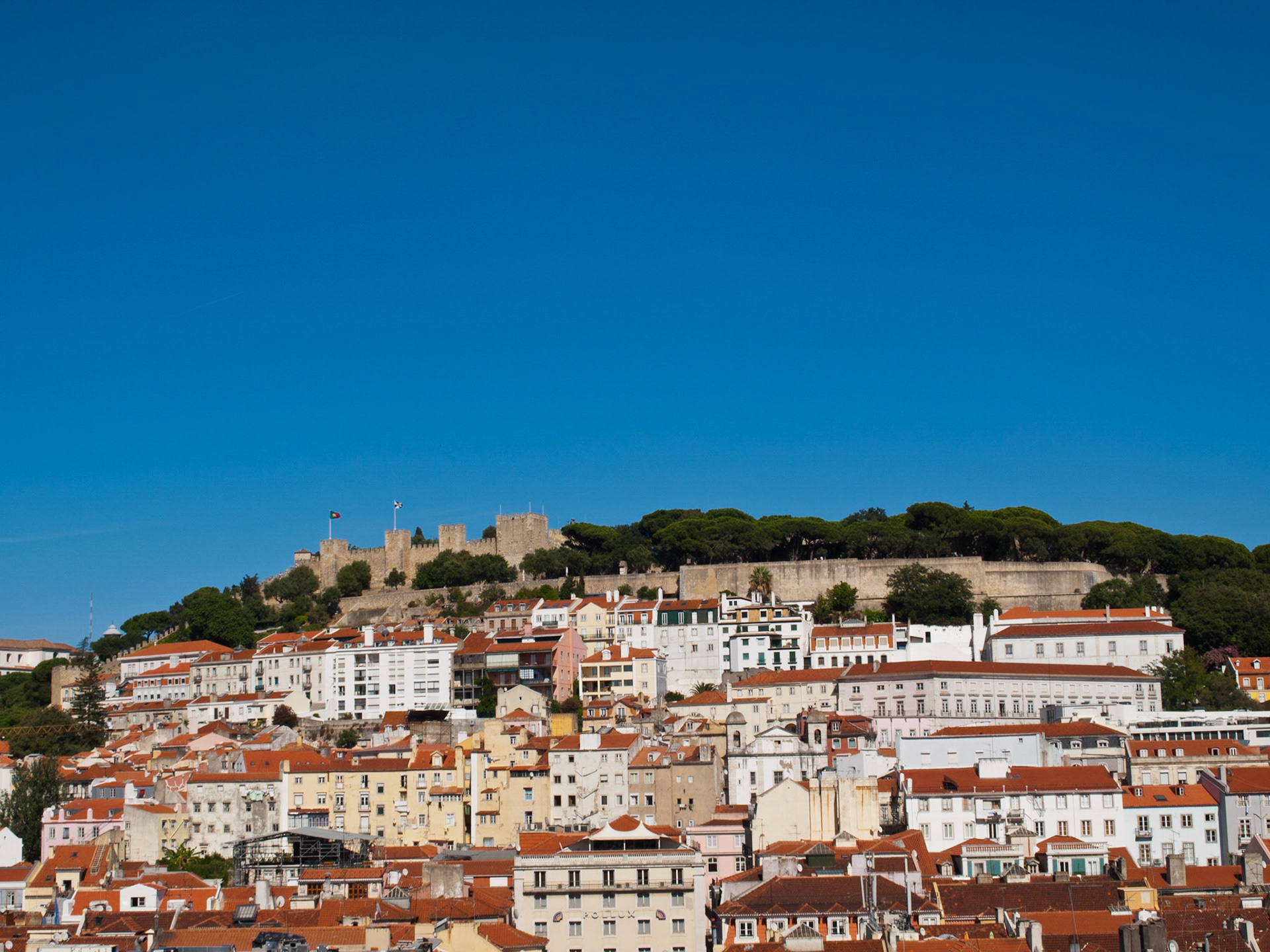 Lisbon St George Castle on top of the hill with houses below and blue sky