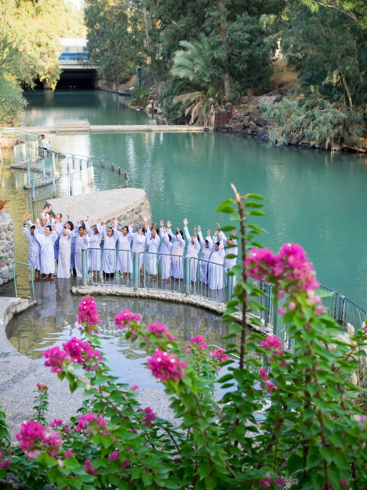 Christian group happily singing with raised arms in Yardenit baptismal site in Jordan river