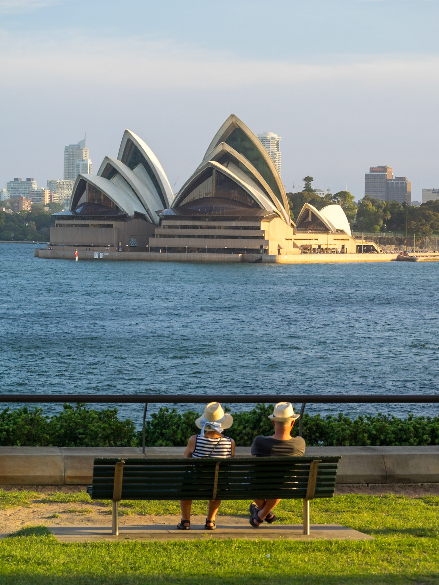 A couple seated on a bench admiring Sydney Opera House from Milsons Point