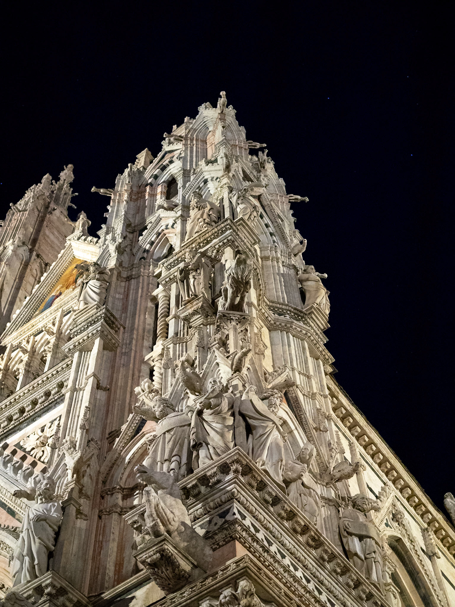 Looking up to the statues covering the right corner of Siena Cathedral facade