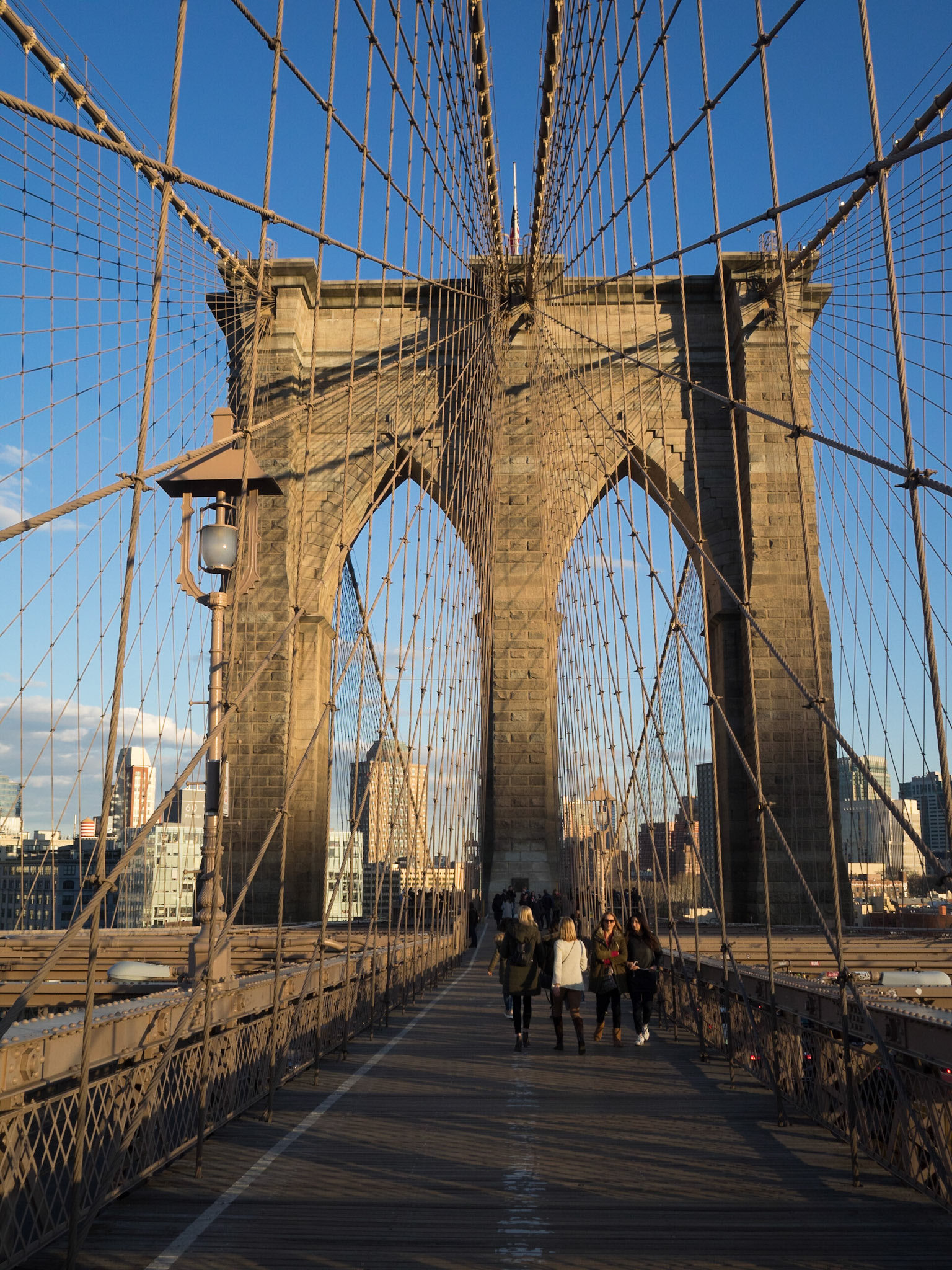 People crossing the Brooklyn Bridge in the sunset light