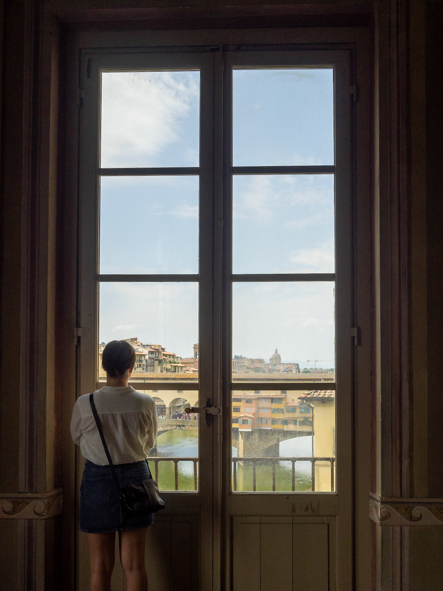 A tourist looks at Ponte Vecchio from inside the Uffizi Galleries, Florence