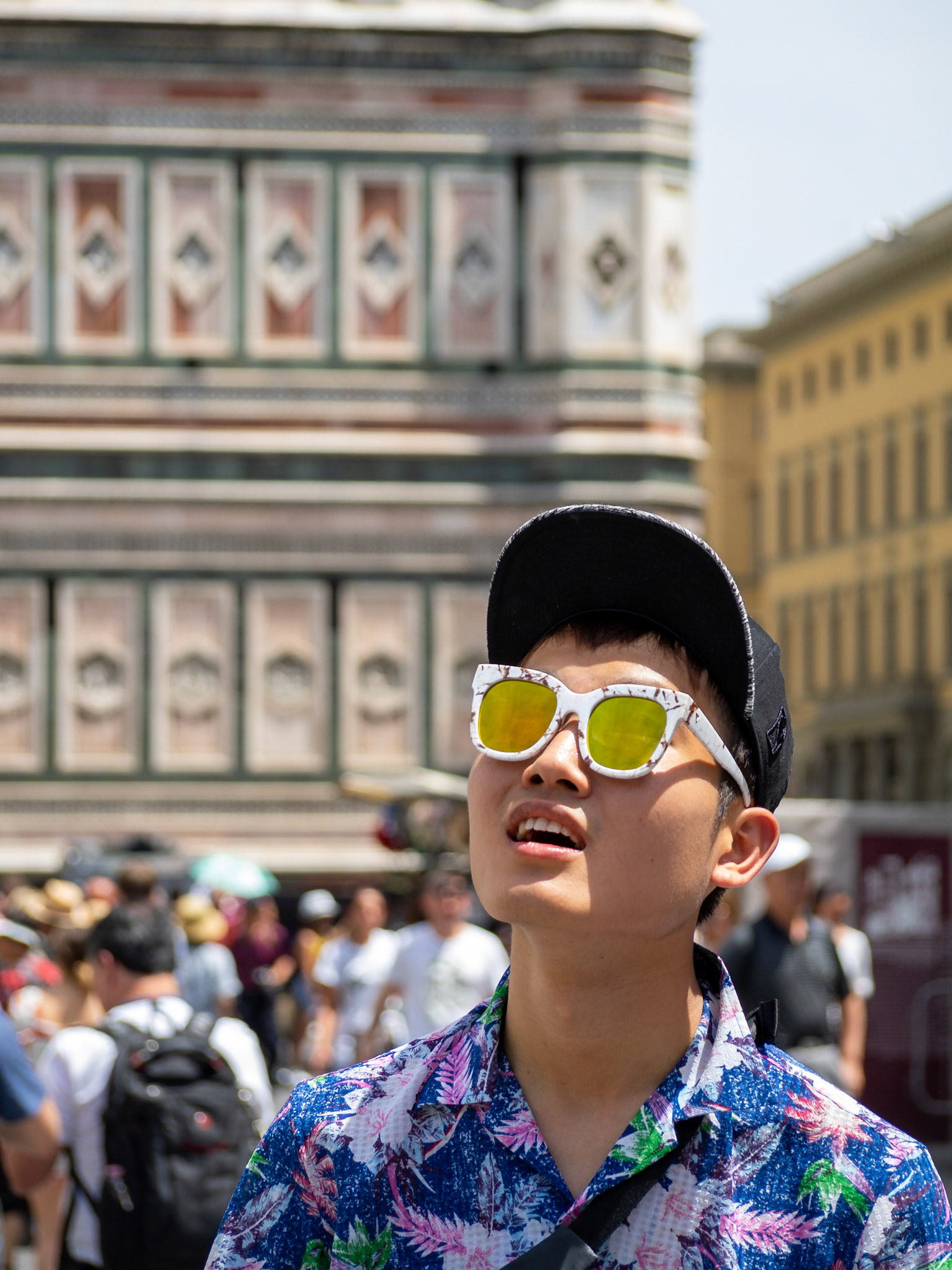 An asian tourists in sunglasses looks up by Duomo di Firenze