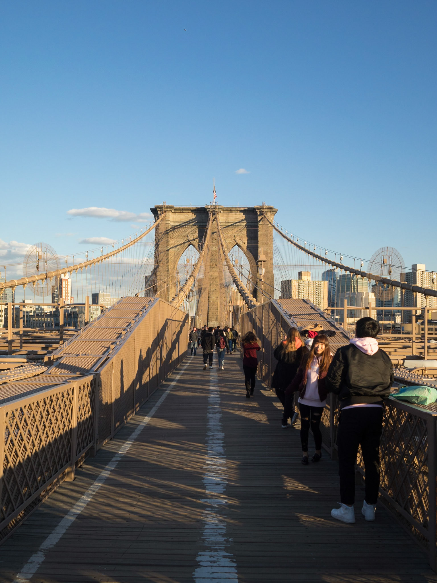 People crossing the Brooklyn Bridge in the sunset light