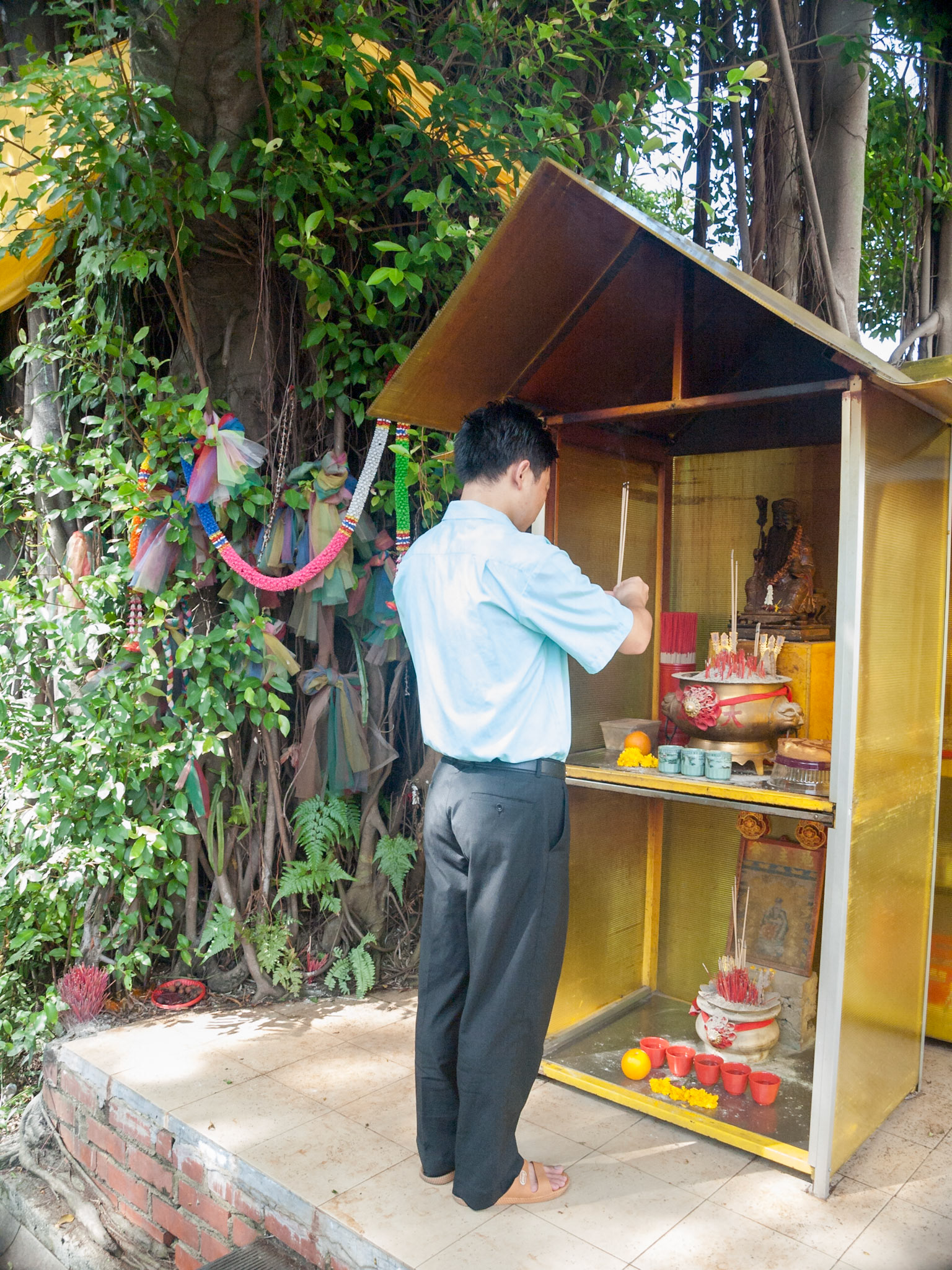 Man praying in street corner Hindu altar