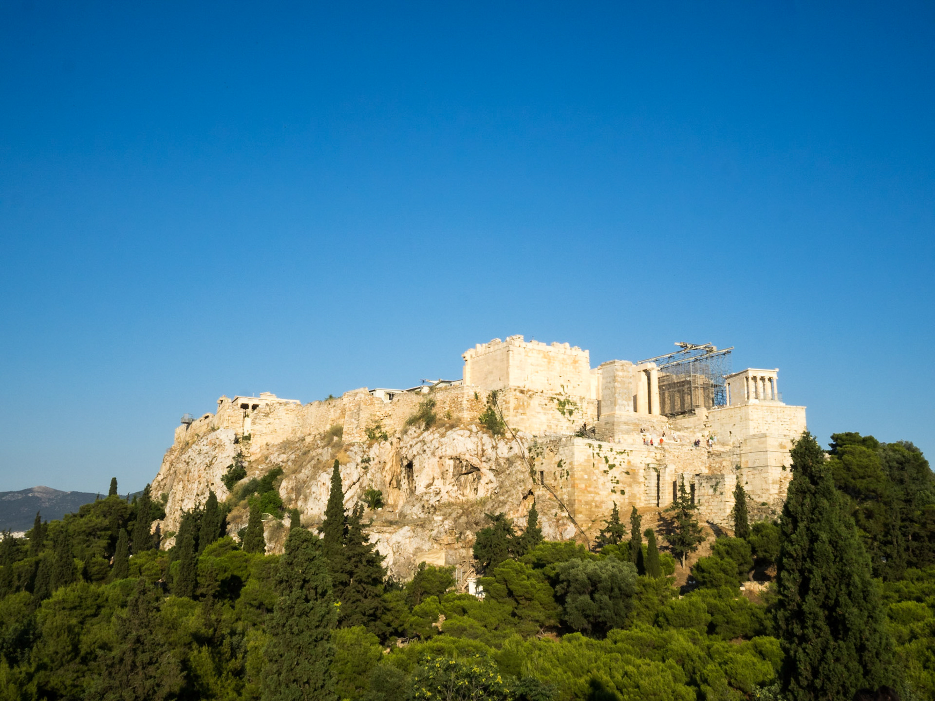 The Acropolis general view over green trees and set against a blue sky background
