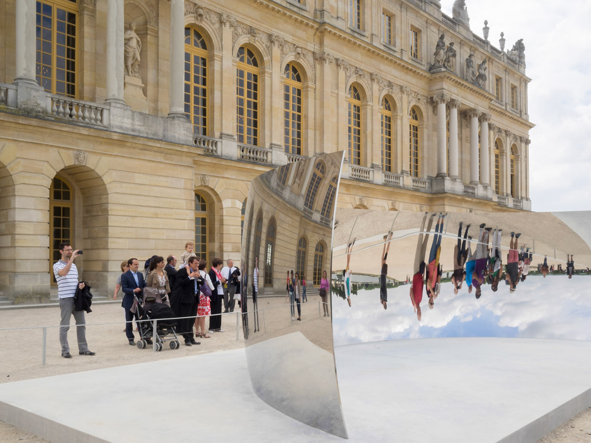 Versailles palace visitors around Anish Kapoor C Curve sculpture installation at the palace gardens