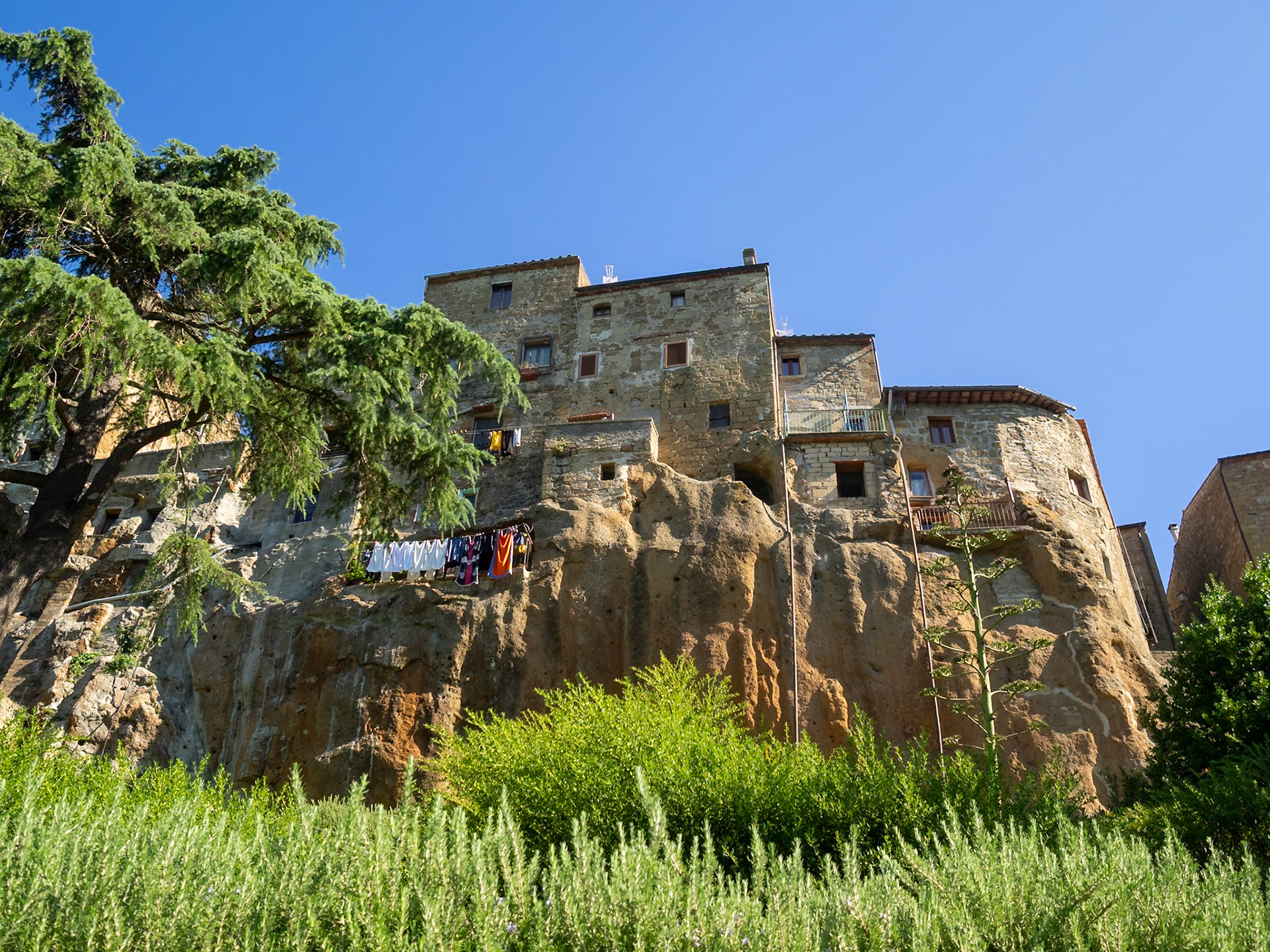 Looking up at Pitigliano stone buildings atop the rock cliff