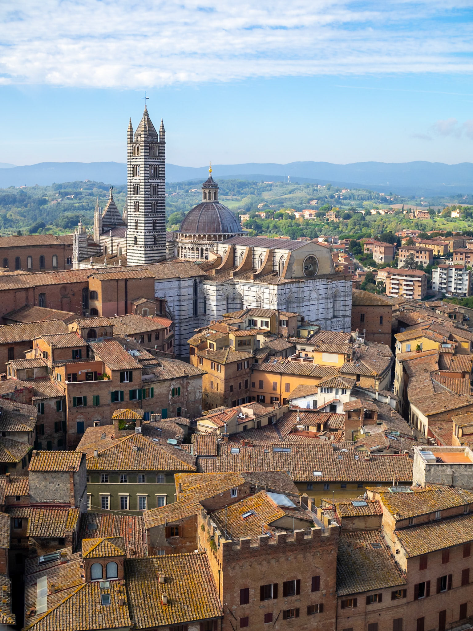 Siena Duomo seen over the buildings roofs with the countryside in background