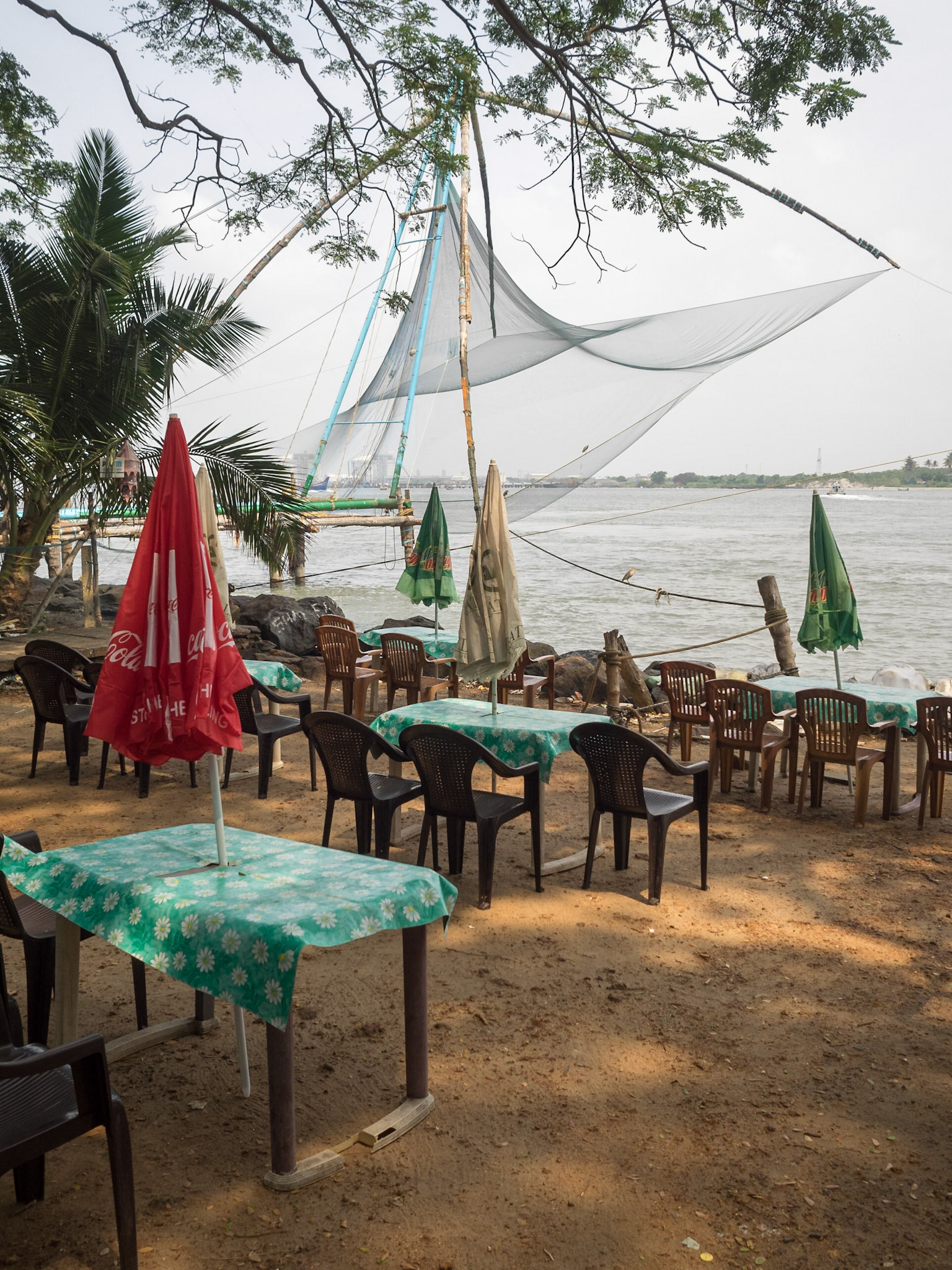 Restaurant tables by the river and the chinese fishing nets of Cochin
