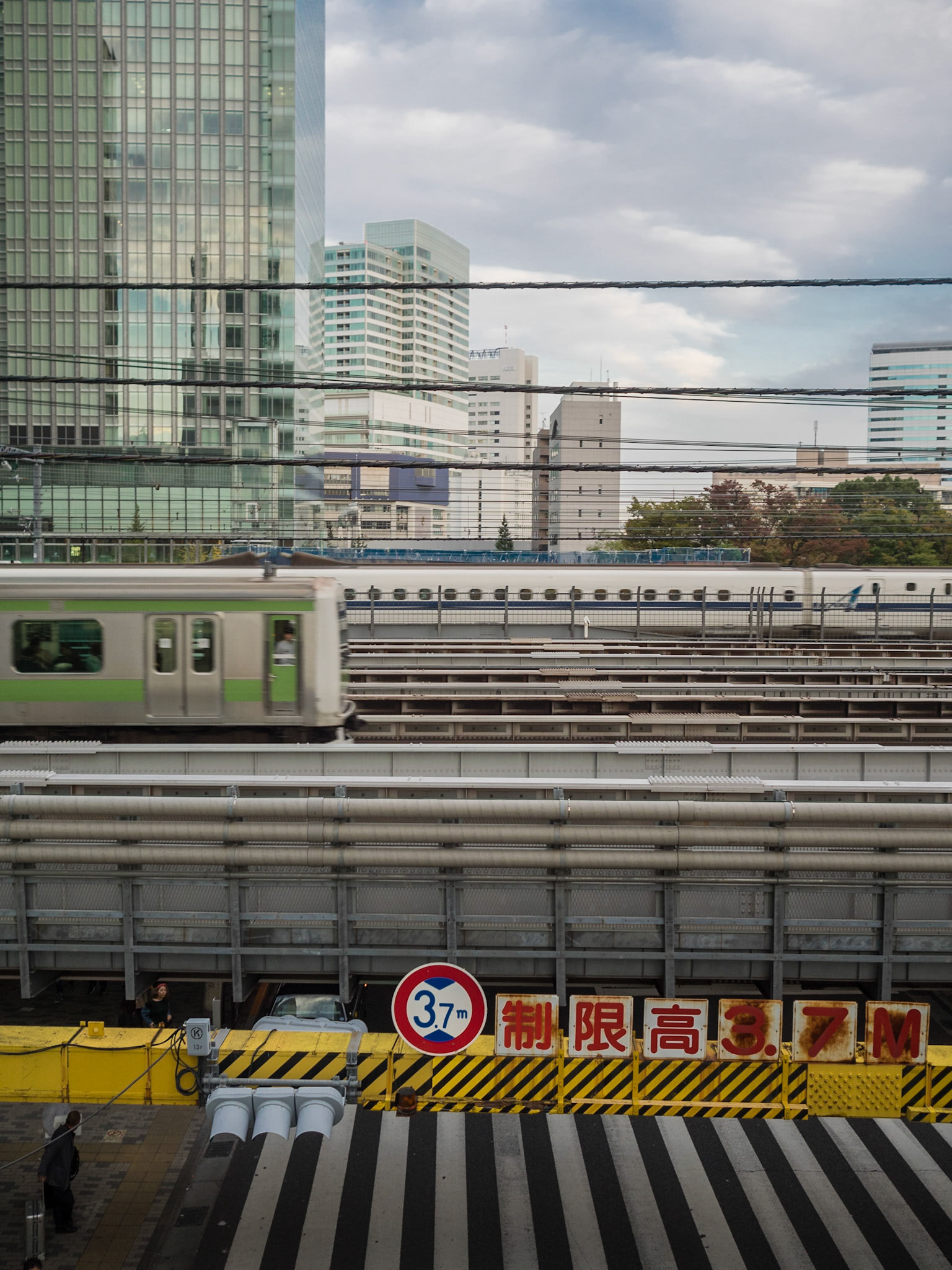 Train lines crossing over road with skyscrapers in background in Tokyo city