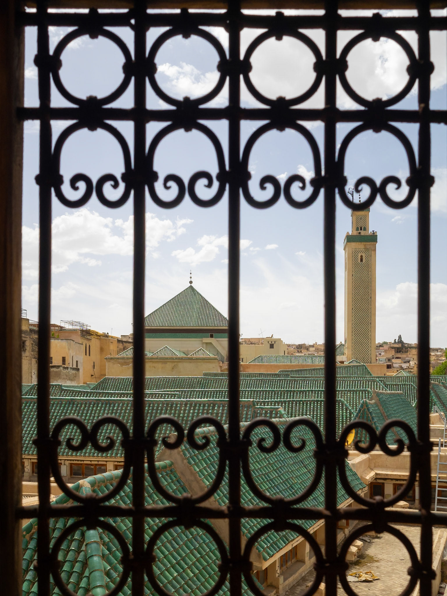 Mesbahiyya Madrasa green tilled roofs seen from a window railing, Fez, Morocco