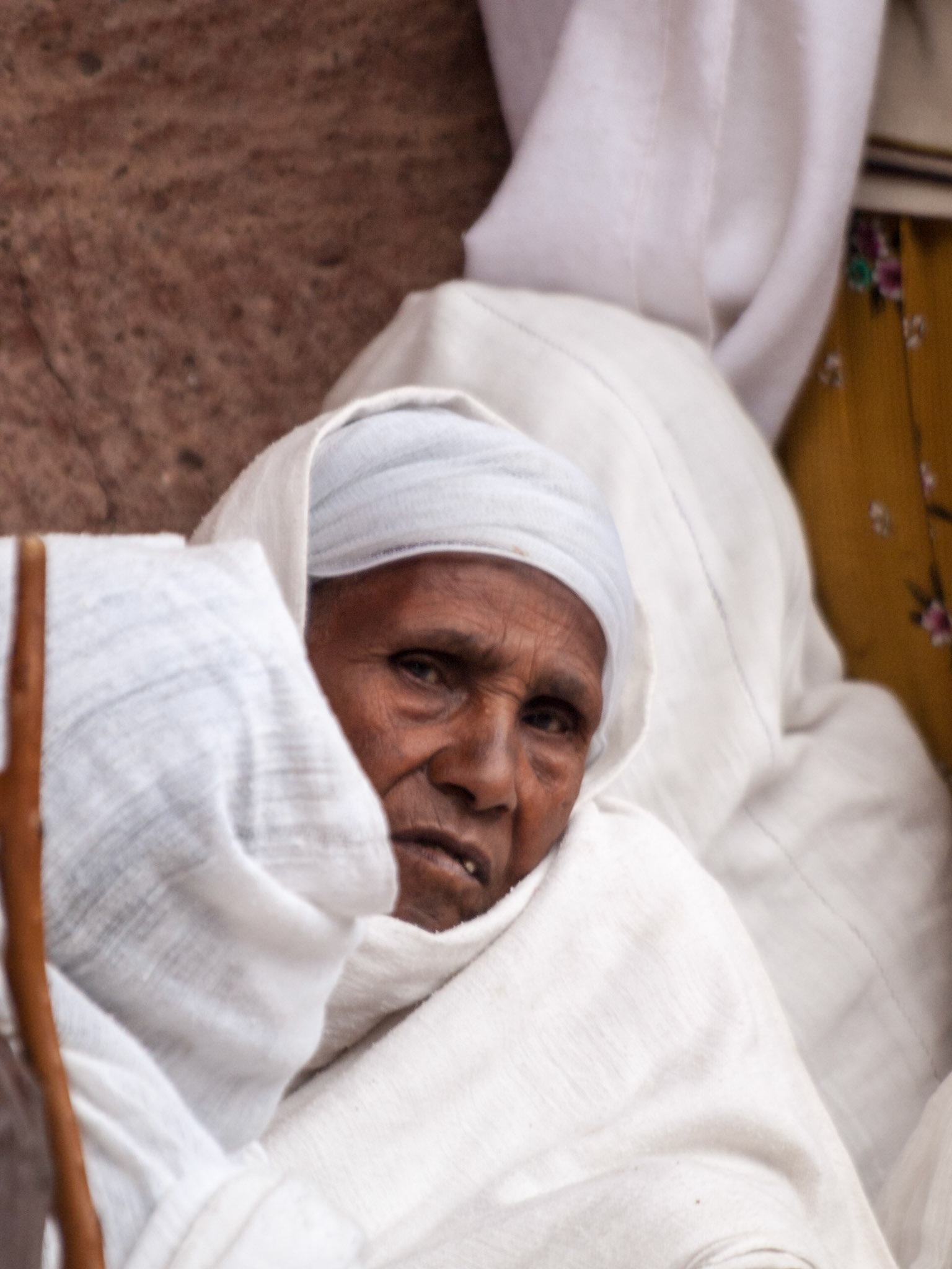 Old pilgrim woman look at camera outside church in Lalbela during Eatser