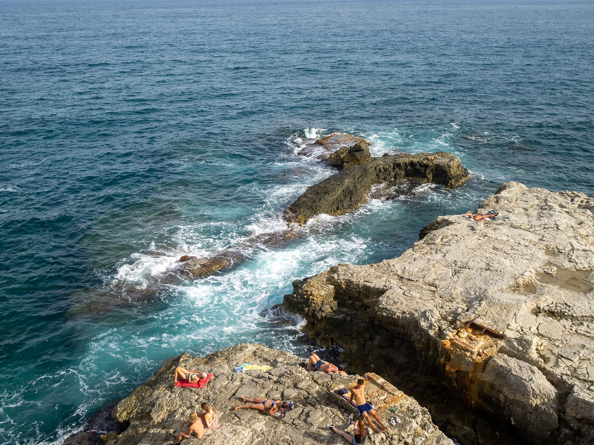 Sunbathing on the rocks by the Mediterranean Sea in Siracusa